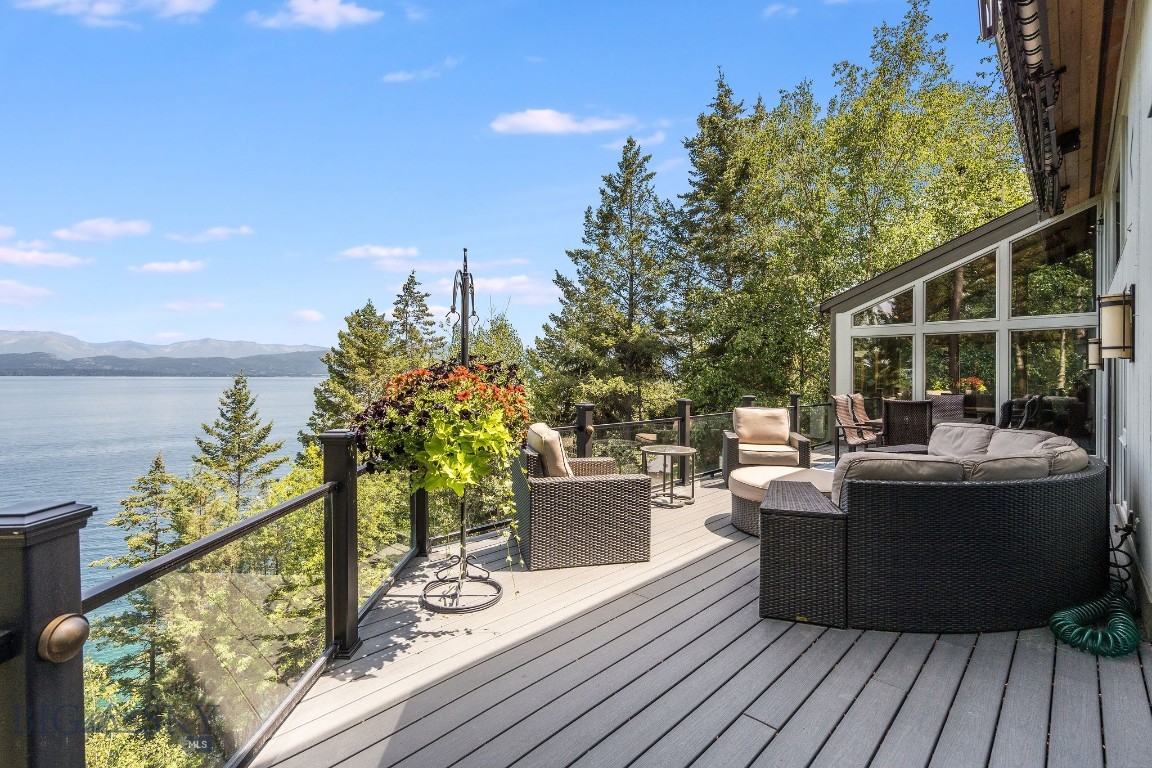 Perched above the sparkling waters of Flathead Lake, this extraordinary luxury estate offers sweeping views of the Swan Mountains & into Glacier National Park. Set on 2.67 private acres, on two lots with 251 ft. of pristine lake frontage, this property blends elegance, functionality, and Montana’s natural beauty. Every detail of this home has been thoughtfully enhanced with premium upgrades. A custom-designed funicular provides seamless access for all ages down to the water’s edge, where a beautifully upgraded dock system awaits, complete with a new hydraulic boat lift & a cantilever double PWC lift with interior catwalk. You will also find a mermaid pond at the water's edge. A charming nature pathway winds through the property, offering a scenic walk to the water. Outdoor living is unmatched with multiple sitting areas designed to take in the views, a cozy firepit for evening gatherings, and expansive decks-completely replaced and upgraded with glass railings to preserve the view. This home offers nearly 4,000 square feet of refined living space, including 5 bedrooms and 6 bathrooms, blending comfort and elegance with room for family and friends. The great room centers around a dramatic floor-to-ceiling river rock fireplace, with soaring vaulted ceilings that create a sense of grandeur and openness. The sunroom is a fan favorite among guests that have enjoyed it over the years, capturing year-round light and lake vistas. Wildlife carvings, including bears etched into the floor tiles, lend a bespoke, artistic touch that celebrates Montana’s wilderness spirit. Recent investments include a new HVAC system, boiler, furnace, paint, window treatments, two 24kW backup generators, and starlink high speed internet. A spacious attached triple garage provides convenience, while the separate heated shop offers ample space to store your boat, recreational gear, and seasonal toys. Fully equipped with a half bathroom, utility sink, and its own washer and dryer, the shop is designed with both functionality and comfort in mind—ideal for lake days, projects, or extended stays. Whether you're savoring the tranquil mountain vistas from the upper terrace, heading out for a day on the water, or simply unwinding in the serenity of your surroundings, this extraordinary Flathead Lake estate offers an unmatched retreat in the heart of Big Sky Country. This property is accessible year-round.