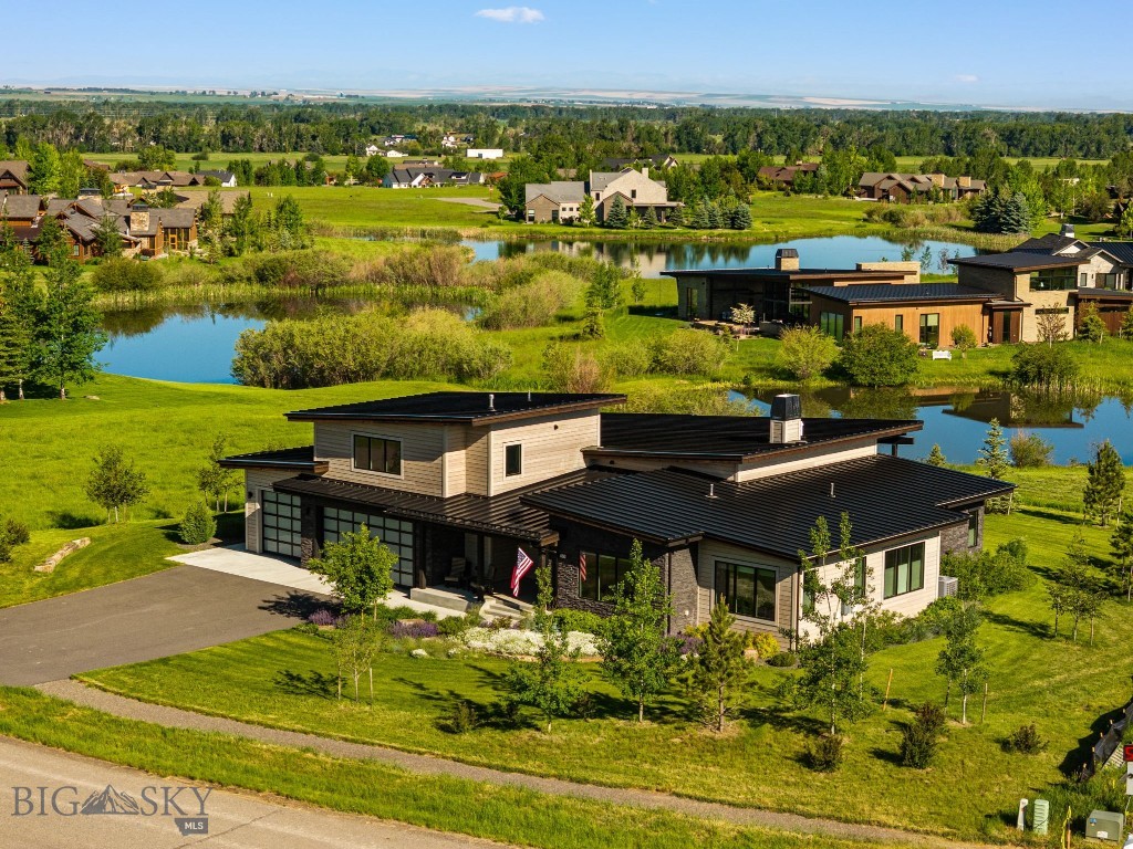 Set on over half an acre along sought-after Brave Heart Loop in Black Bull, this home enjoys a rare backdrop of open space and water views, creating a truly serene setting. This home enjoys a rare backdrop of open space and water views, creating a truly serene setting. Expansive windows immediately draw your eye to the picturesque greenspace and ponds beyond, filling the home with natural light and bringing the outdoors in. The thoughtfully designed floor plan features an open-concept living, dining, and kitchen area ideal for both everyday living and entertaining. The chef's kitchen is appointed with premium Thermador appliances, custom cabinetry, and a spacious butler's pantry. The adjoining living and dining spaces showcase custom wood beams, a gas fireplace flanked by built-ins, and an additional island for added flexibility. The primary suite is a private retreat, offering a spacious bedroom, large dual walk-in closets, a luxurious bathroom with dual vanities, soaking tub, and walk-in shower. A separate guest suite with a private full bath is positioned on the opposite side of the home for maximum privacy. Two additional bedrooms, a full bath, powder room, and a large office that could easily serve as a fifth bedroom complete the main level. Upstairs, an expansive bonus room with a full bath showcases beautiful mountain views and offers exceptional flexibility — ideal as an entertainment lounge, media room, or additional guest suite. The oversized three-car garage features epoxy flooring and abundant storage. Outside, enjoy Montana living at its finest on the covered patio, complete with a plumbed fire pit and hot tub, all overlooking the peaceful open space and water beyond. Combining generous living spaces, quality finishes, and one of Black Bull's most desirable settings, this home offers a rare opportunity to enjoy privacy, views, and convenience in an exceptional location. The Black Bull community includes a pool, fitness center with steam room, private restaurant, golf course, walking trails, cross country ski trails and more. Some photos are Club amenities.