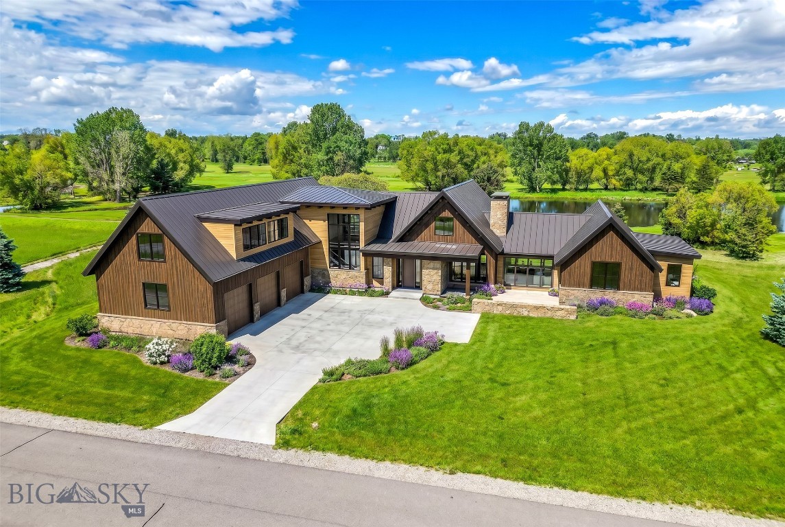 Some things only time and nature can deliver: mature trees that took decades to grow, a pond at your back door, open nature park, and private river access — all on 1.05 acres in one of Bozeman's most coveted communities. Positioned at the western edge of Bridger Lake Meadows — where the development meets nearly 130 acres of deeded open space and the aptly named Dragonfly Pond borders the lot directly — this is one of the most private and tucked-away positions in the entire community. A walking trail along the southern edge of the property leads directly to the pond, through the nature park, and to private East Gallatin River access. Mature pines anchor the property year-round while deciduous trees along the water ignite in color each fall. Wildlife is a daily presence. The orientation is nothing short of extraordinary: an east-facing sun porch perfectly positioned for Bridger Range sunrises, and a large outdoor living space open to Dragonfly Pond for the evenings — both right at your doorstep.
This architectural statement home is worthy of the setting — blending into nature seamlessly while making no compromises on luxury. Natural wood siding, stone masonry, standing seam metal roof, and dramatic black accents read as distinctly Montana from the moment you arrive. A covered entry with stone surround opens into a home built around light, views, and the art of living well.
The chef's kitchen anchors the main level — complemented by a fully equipped back kitchen and a dedicated dining room that flows to a private grill porch. The living room centers on a stunning fireplace shared with an adjacent sitting room, creating two distinct spaces with one warm focal point. Floor-to-ceiling windows dissolve the line between inside and out. The back covered patio — framed by an exposed timber truss gable — is where evenings belong: open to the pond, quiet, unhurried.
The main level primary suite is its own world — capturing views, his and hers closets, and a spa-caliber bath. A three-car garage leads into a generous mudroom with laundry and a second exterior door. A dedicated gym or office with full bath rounds out this wing. Upstairs, three en-suite bedrooms and a landing sitting area offer everything family and guests could need.
Five minutes from downtown Bozeman. Fifteen from the airport. And a lifetime away from ordinary.