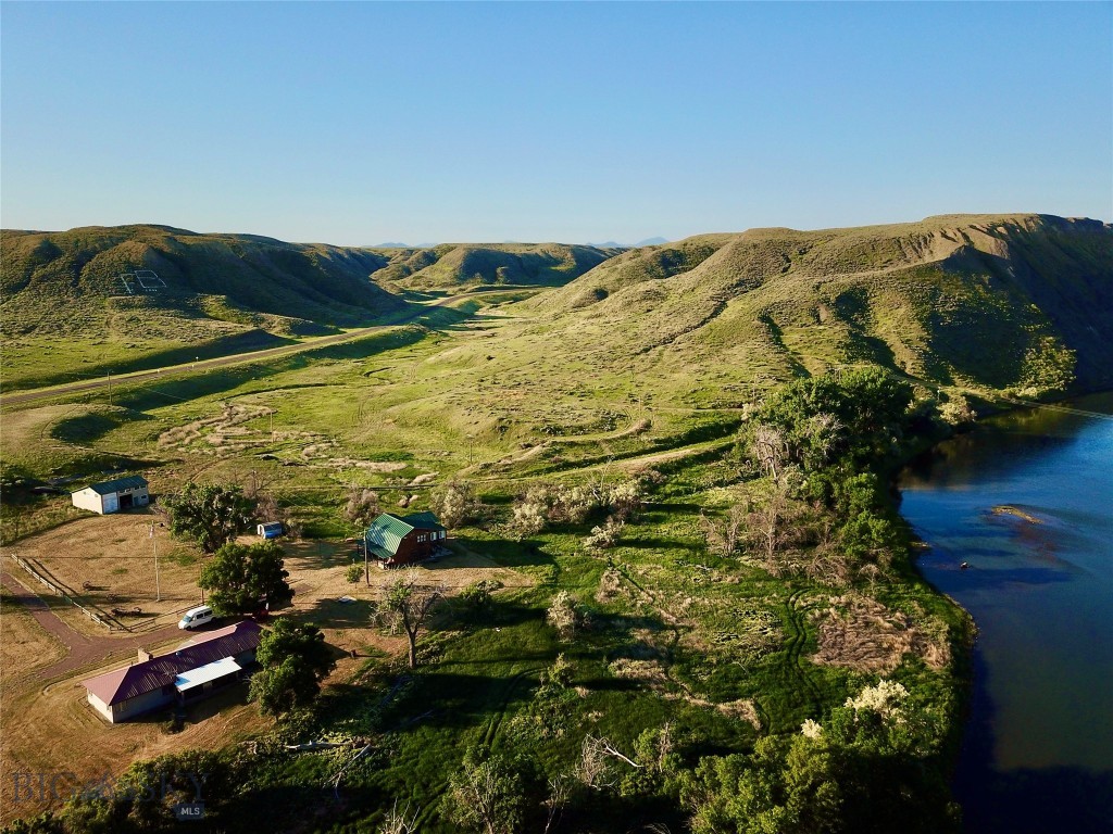 This unique 80-acre riverfront property is located just outside the historic town of Fort Benton. The land offers direct “Mighty Mo” river access and borders public BLM land, making it a prime location for outdoor recreation, tourism, and hospitality ventures. The property includes several structures: a 3-bedroom, 1-bath homestead, a thoughtfully constructed two-story lodge built to accommodate guests or campers, a large shop, and a shed for storage or operational use. The lodge features separate outdoor bathroom access—ideal for use as a base for an outfitting or guiding business, or as a central hub for an RV park or glamping site. With multiple wells already in place and room to expand, the property is well-suited for development. Bordering BLM lands, this location is ideal for launching or expanding a recreational business. Opportunities include guided fishing and hunting services, canoe or kayak rentals, eco-tourism, or establishing a full-scale RV park or campground.