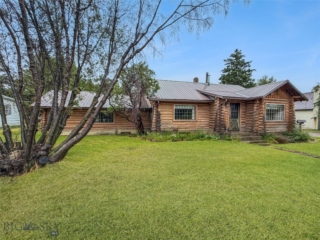 Old fashioned log ranch style house located on 2 lots just a few blocks south of downtown Ennis. This 3 bedroom - 2 bath (both baths are 3/4 baths with walk in showers) home has hardwood floors, open kitchen-dining area, large living room with wood burning stove, newer propane forced air furnace, mature trees, and a full unfinished basement that is perfect for storage. The large master ensuite bedroom has a sliding glass door giving you access to the large yard. There are hook ups for a stack washer-dryer on the main floor as well as a second set of hookups in the basement (no washer or dryers convey). The house is hooked to city sewer and water but also has a well (we believe needs a new pump to be operational) that could be used to irrigate the large lawn (.331 acres giving you elbow room). There is a newly finished 30' x 36' garage set up with one bay created with pass through insulated doors, a second bay (again insulated door) and extra area for work benches or storage. Central vacuum, range & refrigerator would convey at closing without warranty of condition. If you are looking for the older style Montana home then don't miss this one!