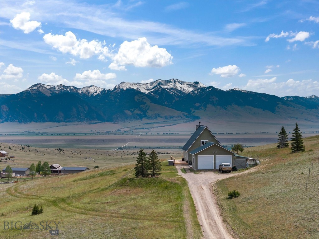 Whether you're seeking a vacation retreat, retirement property, or year-round residence, this thoughtfully finished home in the coveted Shining Mountains subdivision blends comfort, craftsmanship, and world-class Montana recreation. Set in the foothills ten miles south of Ennis, it looks out across the valley to the mountains beyond.

The inviting great room is anchored by a stunning wood-burning river rock fireplace and warmed by wide-plank Arrigoni engineered oak flooring. The showpiece kitchen features Belgian bluestone counters, a full-height 4x16 subway-tile backsplash, a gas range with ducted hood, and antiqued Nova blue tile in a classic Versailles pattern flowing through the dining and entry. The primary suite offers an Arrigoni wood accent wall and a spa-inspired bath with heated Schluter floors, while designer lighting—a Restoration Hardware pendant and Ralph Lauren chandelier—elevates the main spaces. Lutron dimmers, central air, spray-foam insulation, and fiber internet complete the package.

The detached garage doubles as a versatile bunkhouse with a ¾ bath and instant hot water, plus propane heat, plumbed compressed air, and an 80-gallon compressor. Outside, a six-person spa, plumbed outdoor shower and tub, greenhouse, and storage buildings round out the grounds.

The setting is the crown jewel: Varney Bridge access on the world-renowned Madison River, exclusive owner privileges at the stocked Haypress Lakes, and direct access to surrounding BLM and National Forest lands for fishing, boating, hiking, and hunting. This is Montana living at its finest.