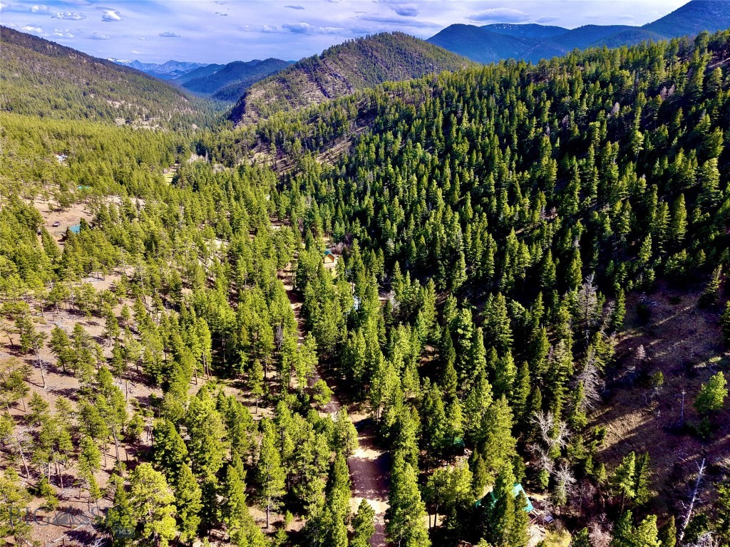Tucked into the Helena National Forest, this classic Montana log cabin radiates on 11.5 acres. As you pull in off the gravel road, the first thing you notice is the quiet, the sound of wind moving through the treetops, the soft rush of Little Wolf Creek, and the distant call of birds echoing through the canyon. Built for comfort after long days outdoors, the cabin offers 2 bedrooms, 1 bathroom, and a loft space, with the kind of warm, rustic character that only a real log home can deliver. Inside, you’ll find a cozy layout designed for making memories — from hunting weekends with friends to quiet winter nights when the woodstove is glowing and snow is falling outside. And best of all: much of the furniture and personal property is included, so you can start enjoying it immediately. Down by the water, a lounge swing near Little Wolf Creek becomes your front-row seat to everything the forest offers. In summer, you’ll hear the creek sliding over smooth stones. In fall, you’ll smell crisp leaves and woodsmoke in the air. In spring, you’ll watch the landscape come alive again — bright green, loud, and fresh.
A major bonus for recreation buyers: this property is set up for the way Montanans actually live.
• Detached oversized insulated 2-car garage (32’ x 28’)
• Quonset (30’ x 24’) with concrete floor
• Plenty of space for ATVs, drift boats, snowmachines, trailers, tools, and hunting gear
Whether you’re here for hunting season, fishing season, or just to escape into the woods, this location puts you in the middle of it all:
• Hiking and camping throughout the surrounding forest
• World-class fishing on the Missouri River corridor
• Holter Lake boating, swimming, and camping nearby
• Hauser Lake and Canyon Ferry for more fishing, water sports, and recreation
• Endless opportunities for exploring public land, wildlife viewing, and backroad adventures
Hunters will appreciate the cabin’s proximity to millions of acres of public land and the region’s reputation for big game and upland bird hunting. Anglers will love being close to some of Montana’s most legendary waters — where early mornings mean tight lines and cold hands, and afternoons mean stories that get better every time they’re told. This is the kind of property that becomes part of your family story. The place where kids catch their first fish. Where friends come for opening weekend. Where the firepit always has one more chair pulled up, and the creek always sounds the same.