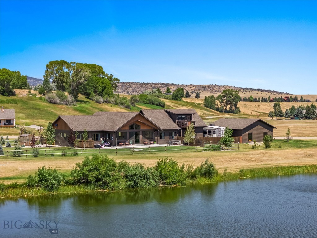 Welcome to your Montana dream home! Nestled on 1.3 acres adjacent to a peaceful community pond, this stunning custom-built home in the Sky View subdivision offers breathtaking, unobstructed views of the majestic Madison Mountain Range. With 3,500 sq ft of thoughtfully designed living space, this home features two spacious ensuite bedrooms plus a large bonus room with its own closet and full bathroom. Perfect for use as an additional bedroom, work out area, or office. Natural light floods the open living area through Andersen windows and a massive 8-foot sliding door, all beneath impressive 15-foot vaulted ceilings (with 9-foot ceilings throughout the rest of the home). A cozy pellet stove adds rustic charm and extra warmth during chilly Montana winters.The kitchen is truly the heart of the home and is a chef’s paradise with KitchenAid appliances, including a refrigerator, microwave, double ovens, and a 5-burner cooktop. Custom walnut cabinetry, quartz countertops, an extra-large island with extensive storage, a farmhouse sink, and a beautiful custom tile backsplash make this kitchen as functional as it is gorgeous. Tucked away nearby is one of the owner's favorite features: a hidden 5' x 10' walk-in pantry. The expansive primary suite is flooded with natural light and offers stunning mountain views. The ensuite bath features a soaking tub with tile surround, a double vanity, a private toilet room, and a custom-tiled walk-in shower with dual shower heads. A generous walk-in closet includes built-in organizers. The guest suite is bright, spacious, and comfortable, complete with a full bathroom, double vanity, and walk-in closet. Multiple thoughtfully designed outdoor spaces for relaxing and entertaining are perfect for soaking in the mountain views, watching wildlife by the pond, or enjoying Montana’s breathtaking sunsets. Fully landscaped yard with 55 trees and maintenance-free decking. There is a 28x30 attached garage as well as a 28x40 insulated and heated detached shop. Every detail in this home reflects quality craftsmanship and intentional design, offering a perfect balance of luxury, comfort, and the peaceful beauty of Montana's wide-open spaces. Whether you’re sipping coffee on the patio, gathering with friends around a fire pit, or unwinding in a private outdoor nook, you’ll find endless ways to enjoy the incredible surroundings. Don't miss the opportunity to call this spectacular Montana property your home!