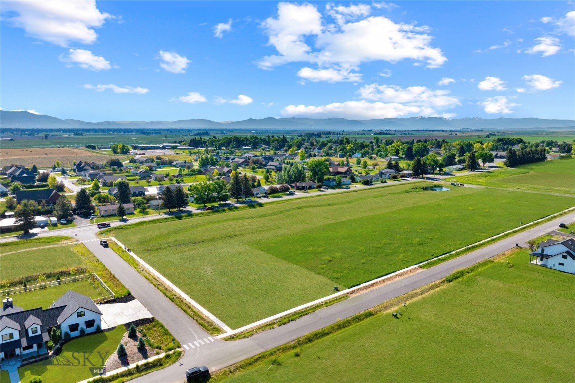 This coveted ½-acre corner lot sits in a walkable luxury development that allows ADUs and backs to open, HOA-maintained park space. The lot is fully equipped for construction with natural gas, power, fiber optic (1 GB download speed), and a community sewer system already in place. Buyer is responsible only for a private well and final plan approval with the builder. Nearby well logs show a strong 30 GPM yield at 241 feet.

Included are thoughtfully designed modern farmhouse plans featuring 4 bedrooms, 4 bathrooms, and just under 4,000 square feet. The home offers both formal and relaxed living areas, a main-level primary suite with ensuite bath and walk-in closet, an open-concept kitchen, dining, and living room, a walk-in butler’s pantry, mudroom/laundry, dedicated office, and a three-car garage. Step outside to an 18’ x 14’ covered patio with a fireplace—perfect for Montana’s indoor-outdoor lifestyle.

A large detached garage/shop is also part of the plans—ideal for trucks, trailers, tools, and hobbies. Above it sits a private-entry ADU with a bedroom, bath, kitchenette, and open-concept living—perfect for guests, multi-gen living, or office use. Driveway access to both the attached and detached garages comes from Goffman Lane on the north side of the property, while the front of the home faces Cushing Lane to the west. This layout provides privacy with the garage and shop shielding views of neighboring properties, while the backyard opens to southern exposure and stunning views of the snow-capped Spanish Peaks.

Enjoy big skies, sweeping mountain views, and the soft soundtrack of crickets and wind in the grass from the surrounding farmlands. Life here moves at a peaceful, steady pace—tucked between Amsterdam and Churchill, where community and quiet still matter. You’ll be near well-regarded K–12 schools offering AP classes and sports across all grades, and just minutes to the Bozeman Airport, shopping, dining, gyms, and more.

Located just 16 minutes to the airport, 15 minutes to Cottonwood Hills Golf Course, and 25 minutes to downtown Bozeman. Outdoor recreation abounds—45 minutes to Bridger Bowl, 1 hr 10 min to Big Sky, and 50 minutes to Hyalite Reservoir. Hit the College ‘M’ trail (30 min), ride ATVs at Pipestone (50 min), or fish the nearby rivers.

However you choose to enjoy Montana, this location puts it all within reach.