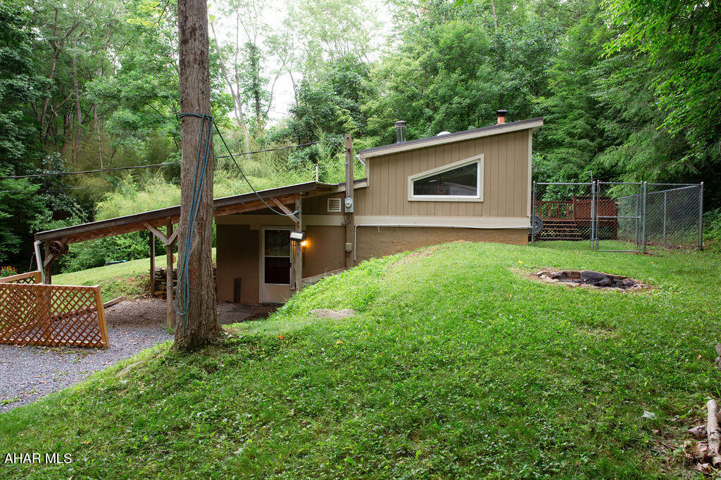 Tucked between Pennsylvania's farmlands and mountains off a gravel lane sits this unique property nestled into the natural slope of the land. The first floor of this property is partially below grade, so it is naturally cooler throughout the first-floor kitchen, open living and dining spaces, bedroom, and first-floor full bathroom and laundry. Skylights and Sky Tunnels stream light into these cozy spaces. Two heat source options warm this home in the winter: a picturesque red woodstove or forced-air oil heat. This 1988 built 1 bedroom, 1 bathroom home evokes an undeniable vibe from its eccentric architecture, but an even more inspiring experience is to be had on the 0.78 acres of outdoor space. A beautiful flower garden cascades down the front yard, a paver walkway leads into a shaded spot along the woodline begging for a bench, and stone stairs step up to a firepit ready to echo campfire songs. Full-time residence, weekend getaway, artistic retreat, or relaxing hideaway - this is an incredibly cool spot.