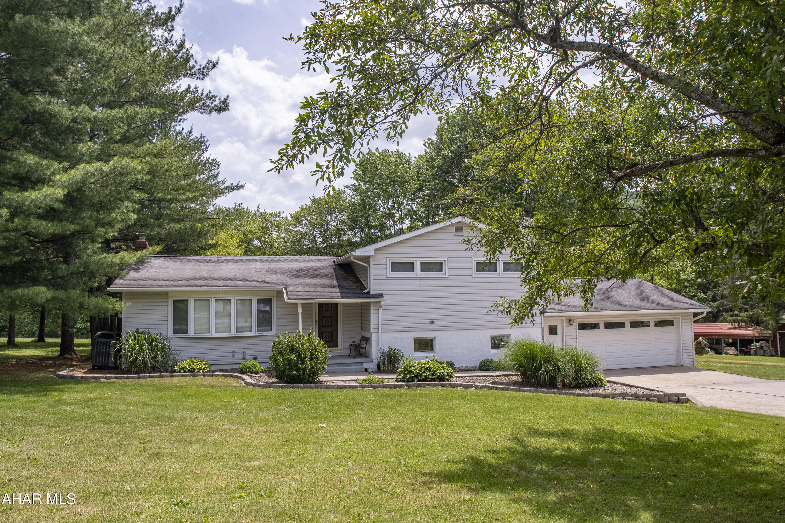 Nestled on just shy of a picturesque acre, this beautifully organized split-level home offers the perfect blend of distinct living zones and seamless outdoor integration. The inviting main level features a bright living room and an elegant dining room that flows effortlessly into a functional, galley-style kitchen, which opens directly onto a lovely back porch. Just a few steps down, the cozy lower-level family room provides an ideal gathering space complete with a convenient bathroom, while the lowest level neatly houses the laundry facilities. The upper level serves as a quiet retreat, hosting three comfortable bedrooms and a well-appointed full bath. Amplifying its exceptional utility and country charm, the property also boasts a two-car attached garage, a separate carport, a small, versatile barn, and a sparkling in-ground pool, making it a true oasis.
