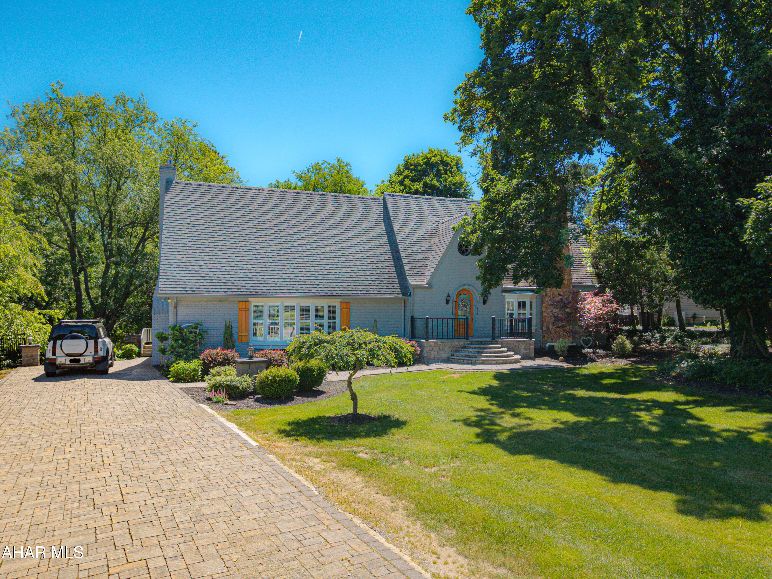 Nestled on a beautifully landscaped double lot totaling 1.852 acres, this stately brick Tudor Revival offers classic architectural character paired with thoughtful modern updates. From the moment you arrive, the home's impressive curb appeal, mature trees, and expansive paver driveway with stone pillars create an unforgettable first impression. Step through the charming barrel-top entry door into the welcoming foyer and discover a home rich in detail and craftsmanship. The formal living room features a stone wood-burning fireplace, elegant crown molding, and hardwood floors that continue throughout much of the home. The formal dining room, also accented with crown molding, provides the perfect setting for entertaining. At the heart of the home, the spacious great room boasts a brick fireplace and flows into the custom kitchen, complete with cherry cabinetry, granite countertops, built-in workspaces, dining space and abundant storage. Just beyond, the inviting sunroom with arched-top windows fills the space with natural light and offers a peaceful retreat overlooking the property. A convenient half bath completes the main level. The second floor offers a private primary suite bedroom with its own full bath, along with three additional bedrooms and a well-appointed ceramic tile hall bathroom, providing comfortable accommodations for family and guests alike. The newly remodeled walkout basement expands the living space with a large family room featuring tile floors and a fireplace, a dedicated laundry area with storage cabinets, another full bathroom, and a finished bonus room ideal for a hobby room, office, or storage. The outdoor living is equally impressive with a covered rear porch featuring triple ceiling fans, an expansive paver patio with a striking stone fireplace, and a separate paver firepit area--perfect for relaxing evenings or entertaining on a grand scale. This property offers timeless Tudor charm and character, exceptional indoor and outdoor living spaces, and only minutes from historic downtown Bedford.