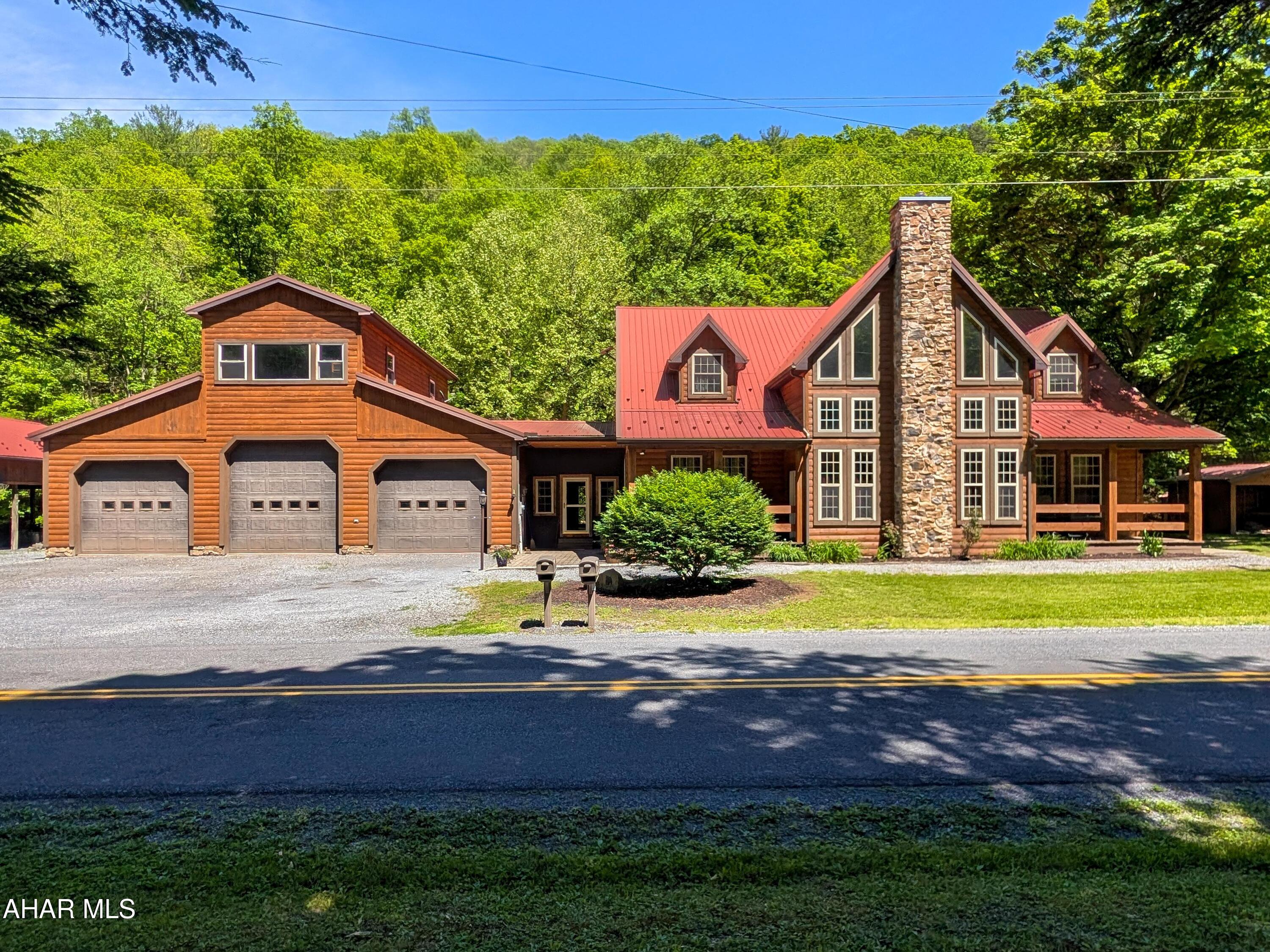Welcome to this breathtaking log and stone home, where rustic lodge charm meets modern comfort. Nestled among nature, this one-of-a-kind property offers stunning views, peaceful surroundings, and exceptional craftsmanship throughout.
Relax on the inviting porches and swings, listen to the nearby stream, or unwind in the unique year-round hot tub room. The property also features a large pavilion, an oversized attached three-bay heated garage, and an unfinished upper level above the garage that offers endless possibilities for additional living space, a home office, workshop, or recreation area. An outdoor wood stove is also in place and ready for future use.
Step through the enclosed breezeway into a chef's dream kitchen featuring high-end appliances, double ovens, abundant cabinetry, expansive counter space, a large walk-in pantry, and a convenient breakfast bar. The adjoining dining area provides plenty of room for family meals and entertaining.
The impressive great room showcases soaring ceilings, beautiful windows that bring the outdoors in, and a stunning stone gas fireplace that serves as the centerpiece of the home.
Conveniently located on the main level are the laundry room, half bath, and an expansive primary suite complete with a walk-in closet and a luxurious private bath featuring a soaking tub and walk-in shower.
An extraordinary staircase with custom handrails leads to the upper level, where you'll find wide hallways, three generously sized bedrooms, a full bath, and a spacious family room perfect for gathering with family and friends.
Comfort is ensured year-round with radiant in-floor heat throughout both levels and central air conditioning. This well-built home was constructed with 2x6 walls, excellent insulation, a durable metal roof, and a generator hookup for added peace of mind during power outages.
Offering 4 bedrooms, 2 full baths, and 1 half bath, this remarkable property must be seen in person to truly appreciate all it has to offer. If you've been dreaming of a private retreat surrounded by nature with lodge-style elegance and exceptional amenities, this is the home you've been waiting for.