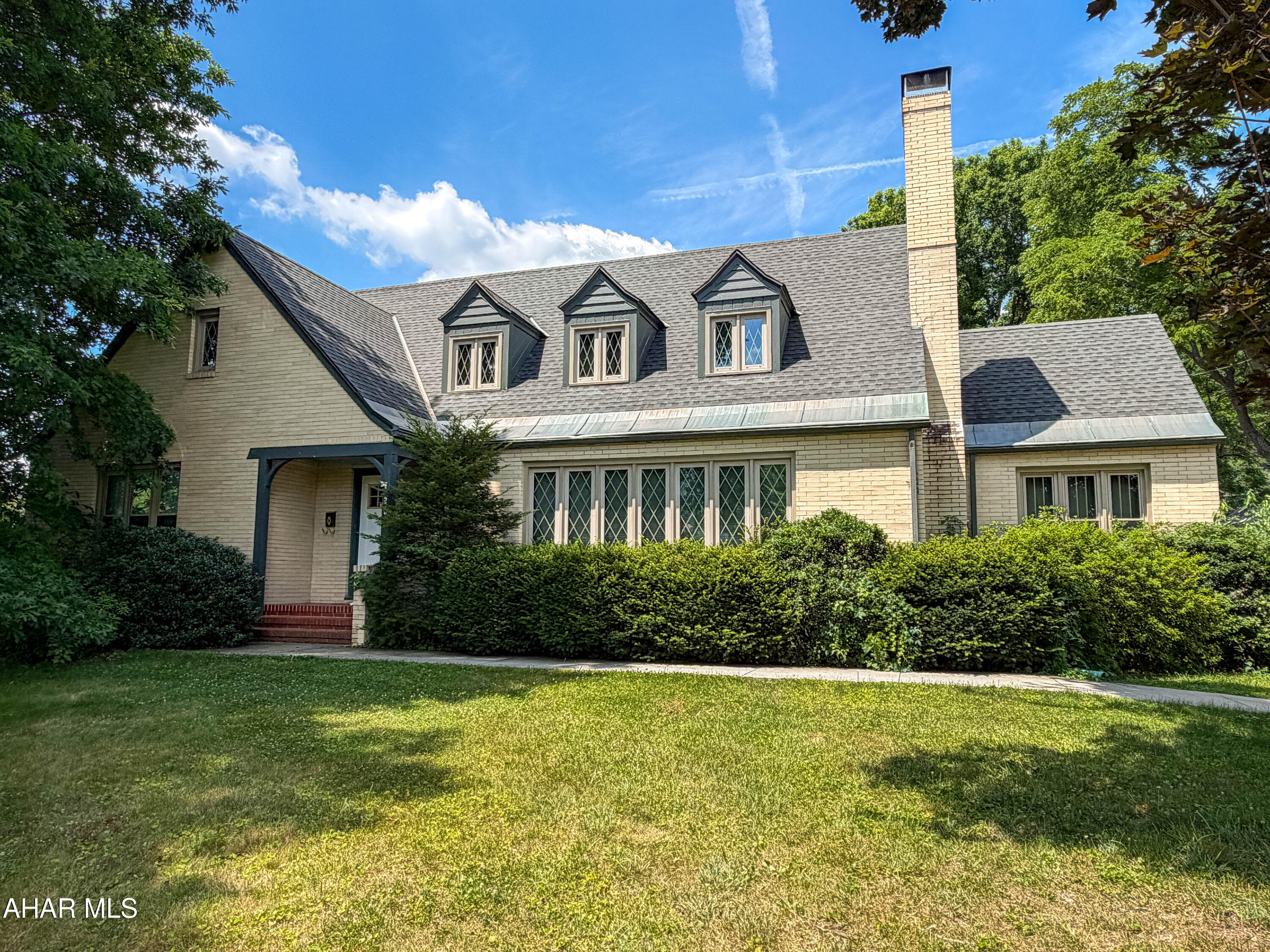 Nestled along one of Bedford Borough's most picturesque streets, this quality brick Tudor home offers timeless character and exceptional craftsmanship. Situated on a large 0.44-acre lot, the property combines classic architecture with thoughtful updates and modern conveniences. The main level welcomes you with a spacious entry area and living room highlighted by a wood-burning fireplace, perfect for relaxing evenings or entertaining guests. A formal dining room provides an elegant setting for gatherings, while the large kitchen features quartz countertops, tiled backsplash, abundant cabinetry, and a charming breakfast nook for casual dining. A cozy den with built-in shelving adds warmth and functionality, while the sunroom offers a bright retreat for reading and downtime. The main floor also includes a private primary suite complete with a walk-in closet and beautifully updated custom tiled bath, a second main level bedroom, another full bath, a half bath, and a mud/service room connecting the home and garage. A covered screen porch is situated just off the mud room. Upstairs, you'll find three additional bedrooms, a full bathroom featuring a soaker tub and shower, plus an office or den that could easily serve as a sixth bedroom or guest suite. The partially finished lower level expands the home's versatility and includes yet another bathroom with a large tiled shower, providing excellent space for recreation or hobbies. Three-car attached garage with a full unfinished loft above that could be finished into a large studio space. Harwood flooring, recessed lighting, new LVP flooring, and Bosch heat pumps with central air-conditioning.  Enjoy the convenience of being just a short stroll from downtown Bedford, the renowned Omni Bedford Springs Resort, the Elks Country Club, and the scenic Heritage Trail.