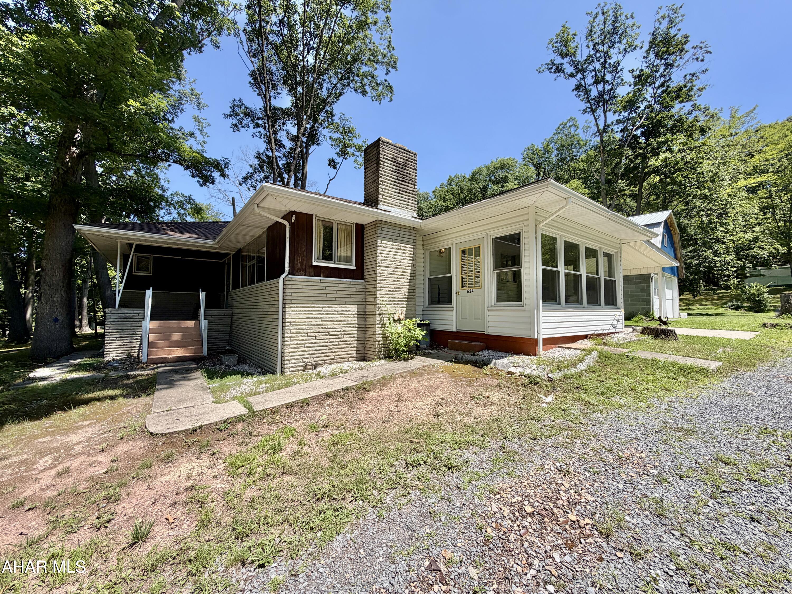 Well-maintained ranch-style home located just outside of town with a 32'x57' garage. The main floor features three spacious bedrooms and 1.5 bathrooms, a welcoming living room with picture windows that fill the space with natural light, an eat-in kitchen providing a great place for meals and gatherings. Throughout the home, you'll find hardwood floors and marble window sills that add a great touch. The full basement offers generous storage options or the potential to create additional rooms. It also features a laundry area equipped with a shower and utility sink. Outside, enjoy an enclosed sun-room, a covered front porch, a large carport that could serve as a covered patio for outdoor dining or lounging, and a two-story, two-car garage. The 32'x57' garage features a 14'x14' overhead door, a 16' high ceiling in the center, concrete floor, electric, and an oil-forced air furnace. Would make a great place to open that small business that you've wanted to start or ample space to store and work on your hobbies. Also included in the sale is a rented mobile home with public water and sewer, offering extra income or living space. AS-IS sale. The seller will make no repairs.