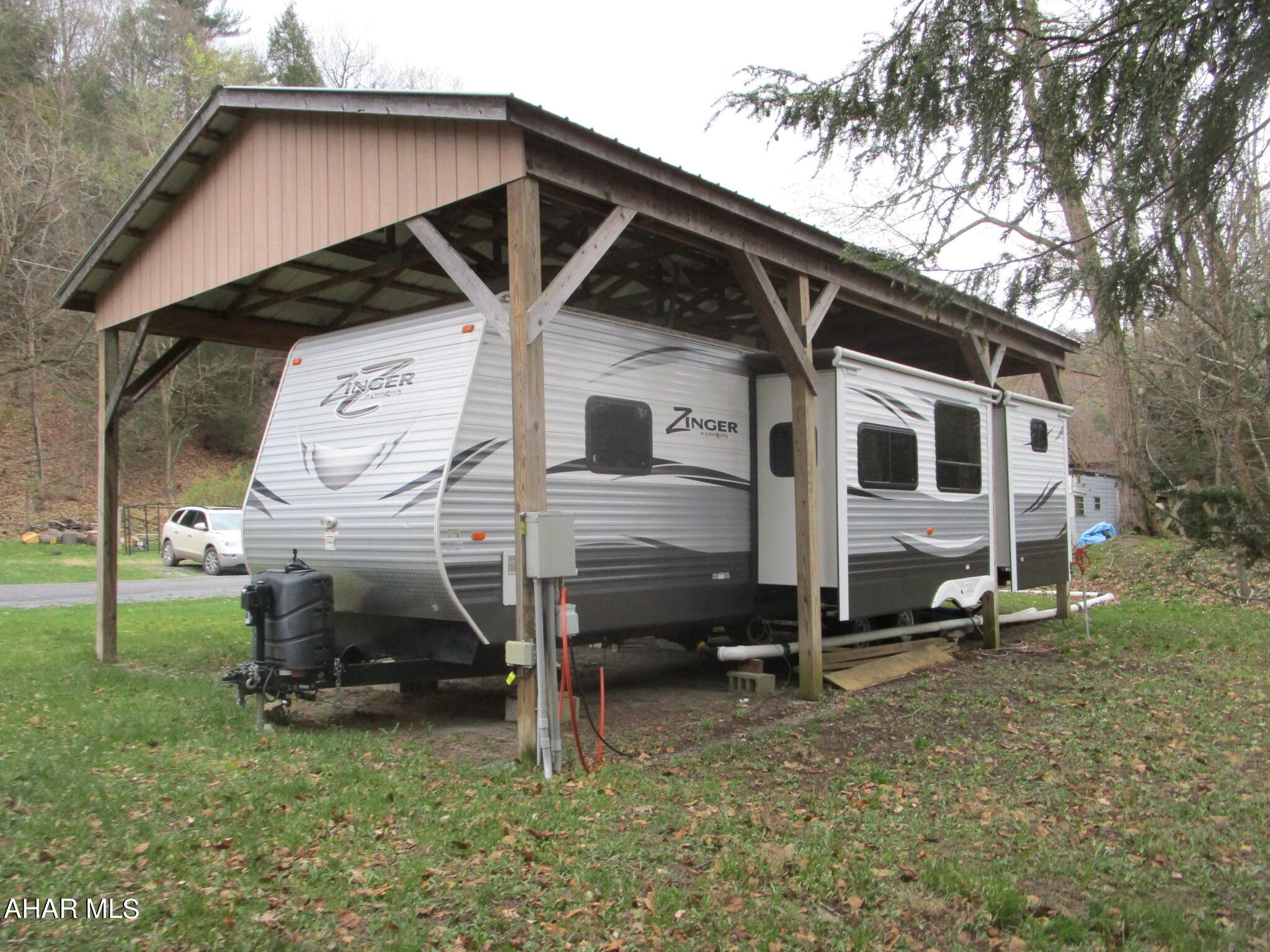 Spacious well maintained camper that sleeps the whole family.  Three tip outs offers extra room inside.  A bedroom and separate bunk room for the kids or guests means beds to sleep in.  But there is also a sleep sofa.  This unit will change camping to glamping.  The inside kitchen has an island.  There is also an outdoor kitchen when you want to eat outside or need more cooking space.  A convenient outdoor shower is included to clean up before entering the camper.  This property has plenty of power with a 100A service.  The 12' x 14' shed has room for your toys and tools.
The camper is covered with a 20' x 36' pavilion with a metal roof for protection.