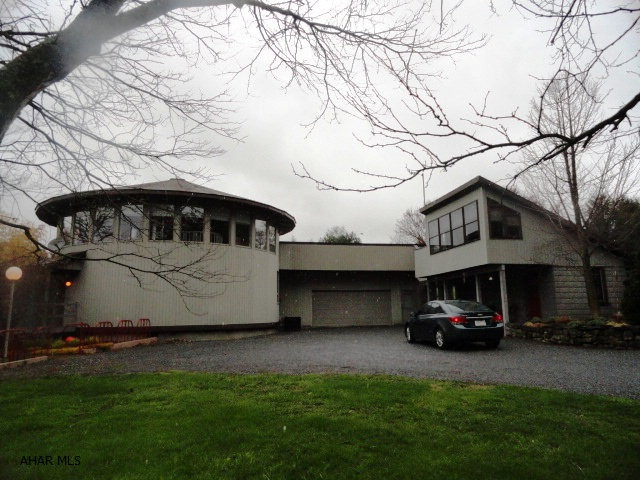 Unique architect designed round house in a very nice country setting! Large room on first floor of house is currently used as an art studio but could be family or rec room. Two car attached garage. Included is a two story cottage with room on first floor with small loft and a sun room on second floor. House is designed for passive solar heat. It also has an electric heat pump.  An outbuilding could be used as carport for storage for motor home or car. Patio with Hot Tub. All of this on 5.17 acres with frontage on Rt 36. Must see inside! All for $225,000