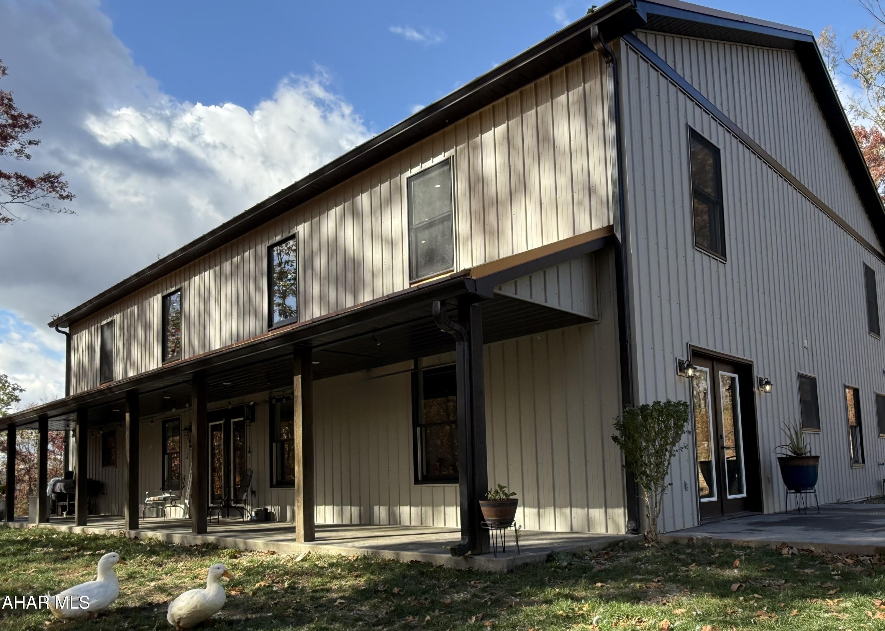 This stunning barndominium combines stunning character with thoughtful modern design and a commitment to energy efficiency. Constructed with exceptional attention to detail, it features radiant two-zone floor heating throughout the main living areas providing year-round comfort and warmth underfoot.

The open layout showcases soaring ceilings and an inviting neutral palette that offers endless versatility and is ready for any style, whether contemporary, farmhouse, or classic Joanna Gaines-inspired charm. Along the entire side of the home, a covered, expansive seating area provides the perfect place to relax and take in both sunrises and sunsets, with panoramic views of the surrounding mountains.

Nestled on 10 very private wooded acres, the property attracts abundant wildlife, including deer, wild turkey, and the occasional black bear. The peaceful sound of a nearby stream adds to the tranquil setting, creating a soothing natural backdrop for outdoor living. A former pond site also offers an opportunity for future restoration if desired.

Inside, the main floor includes three bedrooms, one currently used as an exercise room along with a convenient laundry room with exterior access. Upstairs, two additional bedrooms and two loft areas provide flexible living space, while the home features two full baths and a powder room on the first floor.

The master suite is a true retreat, featuring private French doors that open onto a secluded patio overlooking the natural surroundings. It offers a spacious walk-in closet and a thoughtfully designed bath with a soaking tub, an expansive tiled walk-in shower, and dual sinks for added convenience.

The garage, located just steps from the home, was thoughtfully designed to accommodate an apartment, workshop, or home office. Once completed, it could serve as an exceptional extension of the living space. Its proximity to the main home also allows for the future addition of a covered walkway between the two structures.

Located just minutes from I-99 and Route 30, this peaceful retreat offers easy access to major destinations including Washington D.C., Baltimore, Pittsburgh, and Philadelphia via the Pennsylvania Turnpike.

This exceptional property blends thoughtful craftsmanship, comfort, and connection to nature creating a serene and timeless place to call home.