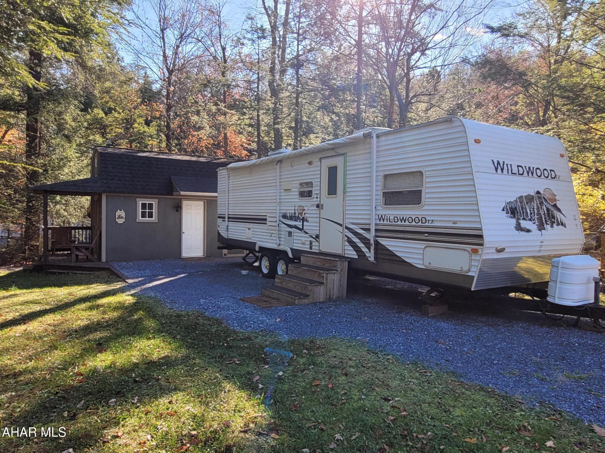 Semi-private campsite with camper and extra sleeping room and bathroom in shed.  Camper  has a slide out that offers extra room inside.  It features two bedrooms along with a futon and a bath.  Inside the shed is a loft bedroom along with kitchen/living space area on the ground floor and a full bathroom.  The outside area has seating around your fire pit area.  Campsite is wooded and is adjacent to a creek.  Enjoy nature and all the amenities of Glendale Yearound as well:  swimming pool, clubhouse, tennis/basketball/volleyball/horseshoes, two playgrounds, dog park, planned activities, catch and release pond and more.  
Pictures do not show the camper with the slide out open.