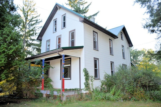 Beautiful setting for this farm house with two car garage.  Some work has been done to the interior and it will be worth the effort to finish the job. New roof.  Newer vinyl siding and windows.  Acreage is partly wooded.  Some open fields.  Property is being sold As Is.