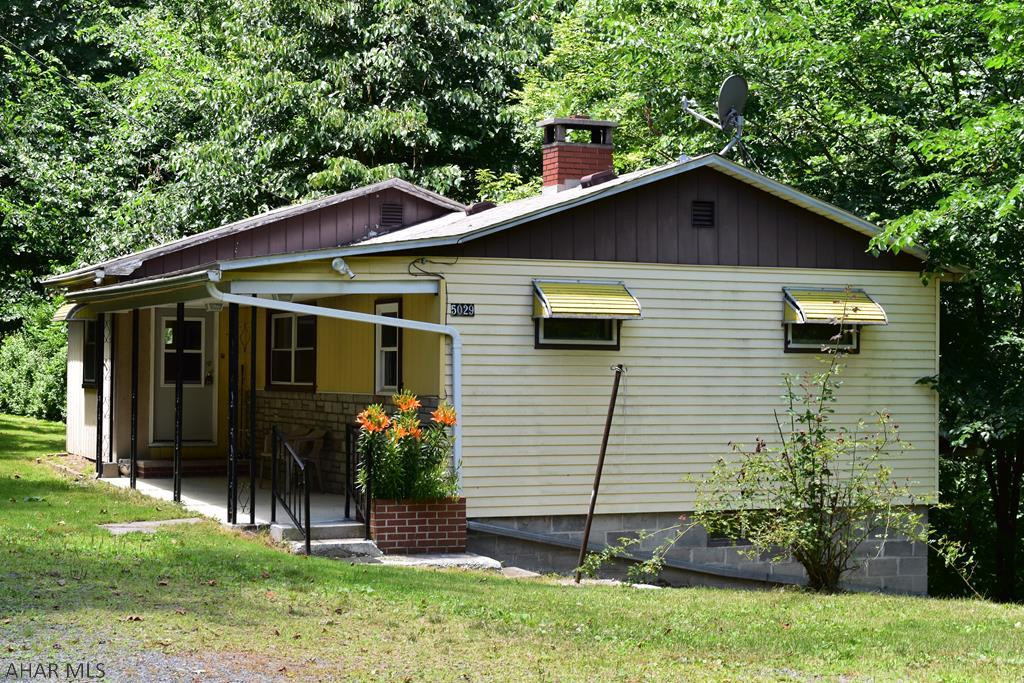 Quaint 1 story home nestled on wooded lot with covered porch.  Hardwood floors and stone fireplace are sure to impress.  Being sold as is.
