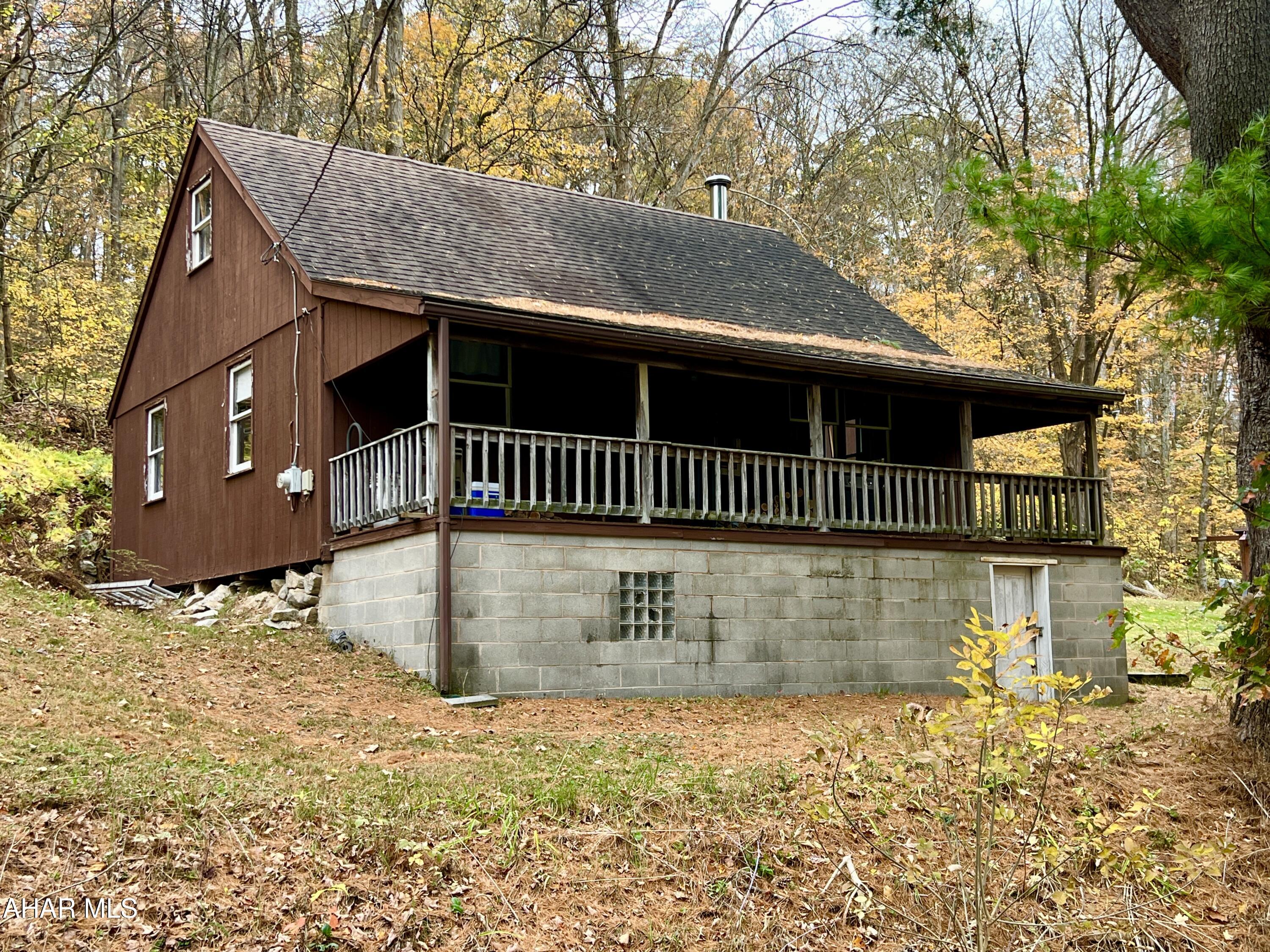 Escape to nature with this cabin nestled on nearly 2.5 acres, bordered on three sides by PA State Game Lands 261 consisting of 3,220 Acres. Perfect for hunting, fishing, boating, and hiking, this property offers an ideal retreat just 20 minutes from Lake Raystown and minutes from the Juniata River and H&BT trails. The cabin features a main-floor bedroom and a spacious loft area to comfortably sleep all your guests. It includes a 3/4 bathroom, living room, kitchen, and a covered front porch perfect for relaxing and enjoying the outdoors. The Seller just had a 1500 gallon septic holding tank installed.