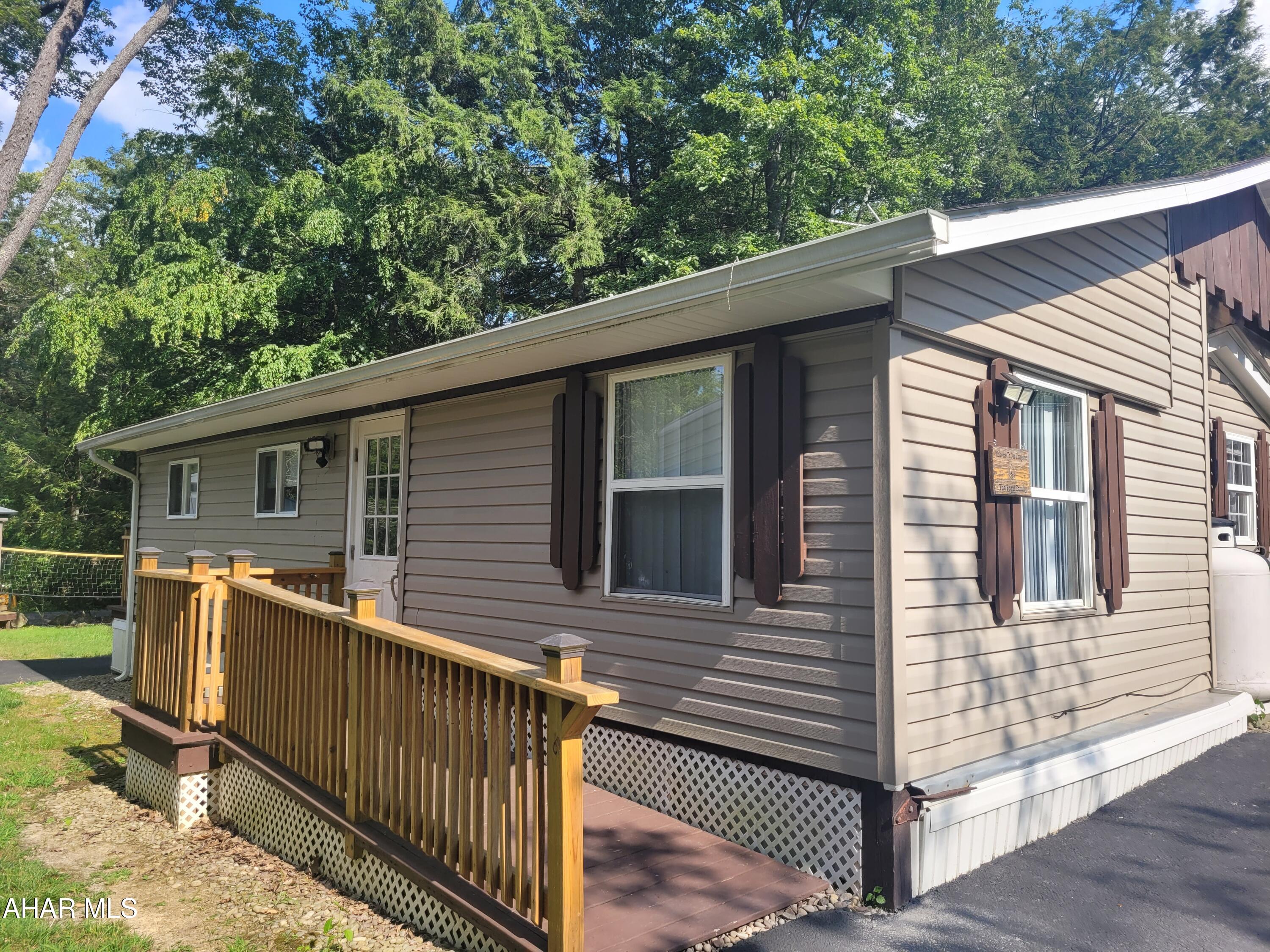 Enjoy the ambiance of camping with the comforts of home.  Whether you are looking for a place for the whole family to get away to, or a cozy full time residence you need to take a look at 115 Brookside Circle.  Start with the paved driveway.  Enter into family gathering room which is over 200 square feet.  But there is more:  two bedrooms, another living space, a kitchen with a nook and a stackable washer / dryer.   Outside the cute pavilion allows you to cook on the amazing grill regardless of the weather.   Or make a few mountain pies while visiting around the fire pit.   The storage shed will hold your toys and tools.