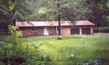House is under roof, completely framed out, well & septic, electric to property.  1 acre with trout stream, front yard, very private, cedar siding.  1 story, 2 car attached garage.