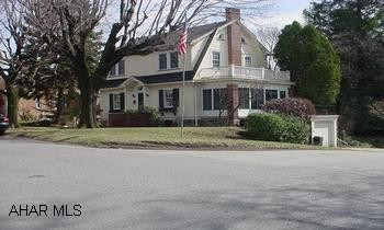 Charming Dutch Colonial. Large Living room with wood burning fireplace, book shelves, hardwood floors and French doors to 3 season porch.