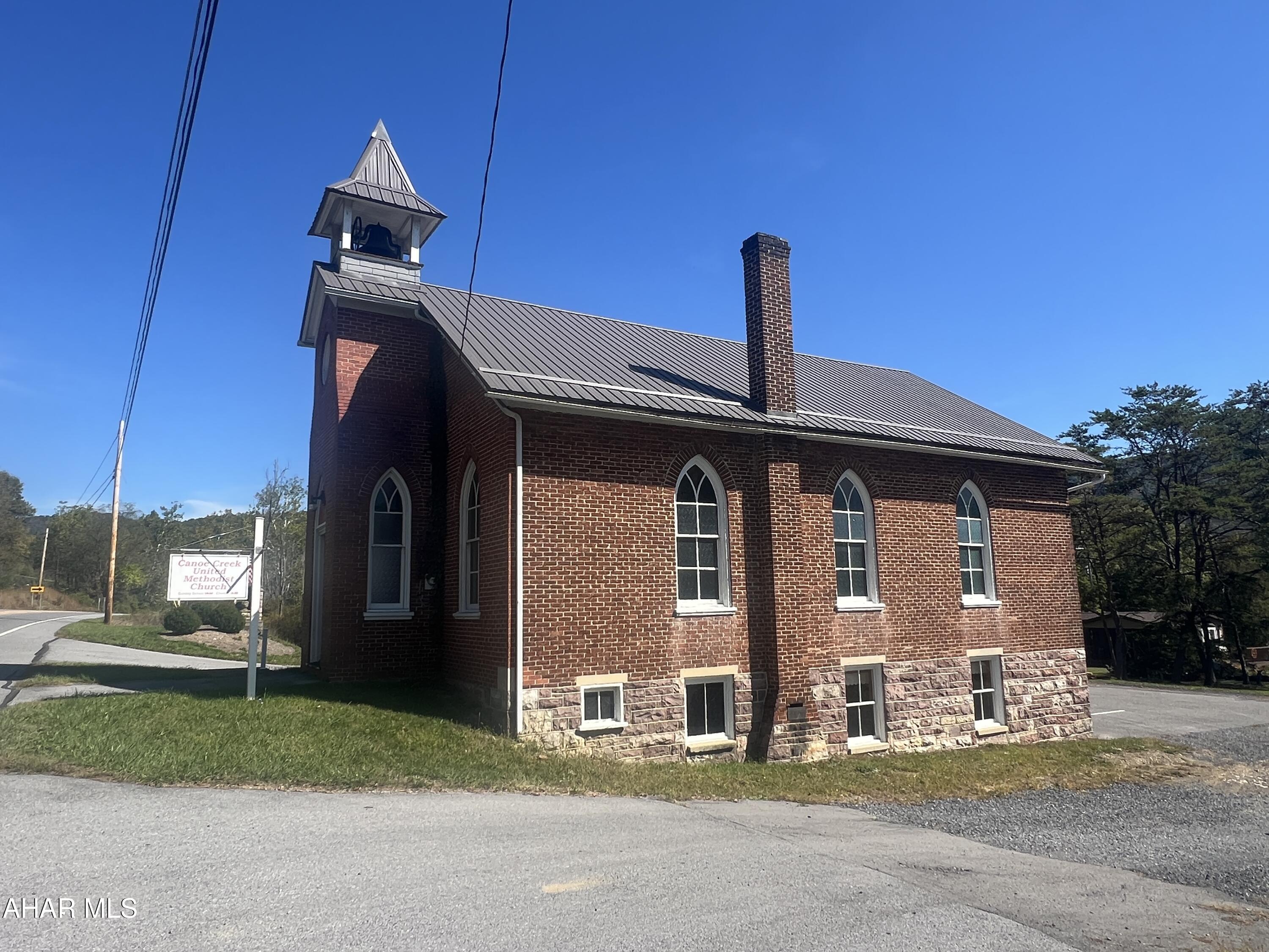 Discover a unique opportunity along the high-visibility Route 22 corridor in Frankstown Township, Blair County. Built circa 1921 and situated on approximately 0.29 acre, this 1,395-square-foot brick and mountain stone building combines historical character with modern updates. The property is zoned M-F (Manufacturing-Farming District) within the Hollidaysburg Area School District, offering a range of potential uses for a discerning buyer or investor.

Step inside through double raised-panel wood doors into a welcoming foyer featuring two stained glass windows, a hanging light, bell rope, and access to the main sanctuary. The sanctuary showcases timeless craftsmanship with oak floors, carpet runners, 20 wood pews, two ceiling fans, and eight cathedral-shaped stained glass windows. The raised pulpit area includes a communion rail, pulpit furniture, and a Hamilton piano, creating a warm and authentic setting. From the pulpit, stairs lead to the finished lower level, which also has an exterior entrance and handicap-accessible ramp. The lower level features two newly constructed ADA-compliant restrooms, a new drywall ceiling, a furnace room with a 275-gallon oil tank, nine windows, and an exterior door leading to the paved parking lot.

The property is served by a new well and a 2,000-gallon holding tank. Systems include a 100-amp breaker panel and a Luxaire oil forced hot air furnace. The exterior has been recently improved with a new metal channel-drain roof, vent ridge, spouting, snow guards, and a bell tower. Additional exterior highlights include concrete steps with vinyl handrails, a vinyl signpost, security lighting, and direct driveway access from US Route 22.

Located just minutes from Historic Hollidaysburg, Canoe Creek State Park (958 acres), the Frankstown Branch of the Juniata River, and State Game Lands #147 (9,254 acres), this property offers a versatile setting ideal for a small business, studio, workshop, community use, or adaptive reuse project. Its blend of craftsmanship, visibility, and rural charm makes it a truly special property in Central Pennsylvania.