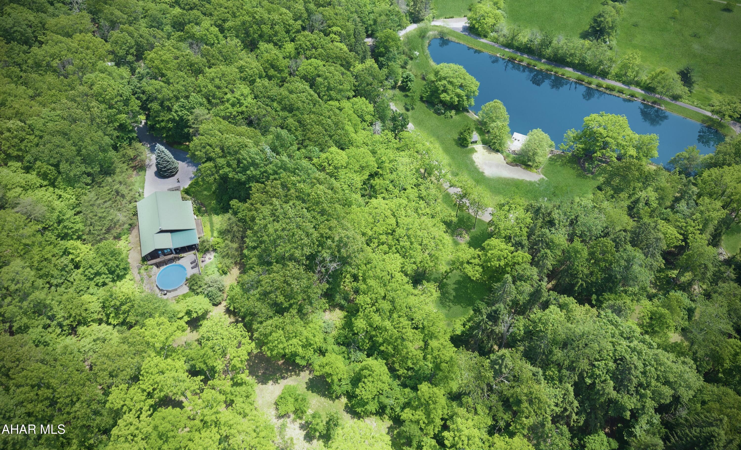 Tranquil 26-Acre Retreat with Pond, Views & Pool in Bedford County

Welcome to this peaceful 26-acre retreat in historic Bedford County, where privacy, nature, and quality craftsmanship come together in perfect harmony. Built by one of Bedford's premier builders, Bill Waltman, this custom home offers thoughtful design, timeless appeal, and breathtaking surroundings.

The centerpiece of the property is a gorgeous pond with a flagstone patio and dock—a dreamlike setting for reflection or entertaining. From the house, deck, and patio, take in dramatic sunsets and peaceful sunrises, both beautifully reflected across the water. These golden hours add a magical quality to the already serene landscape, with seasonal views of the Allegheny Mountains providing an ever-changing backdrop.

The home sits elevated above the pond on a gentle slope, with architecture that maximizes its serene vistas. Inside, rustic-inspired design and warm, organic finishes create a seamless connection between the indoors and outdoors. The sunken living room with expansive windows opens to a covered porch, perfect for outdoor dining and views of the beautifully landscaped pool.

The primary suite is a private retreat, with windows on three sides, ample closet space, and a spa-like bath with a soaking tub. Three additional bedrooms are located in a separate wing for added privacy. The open-concept kitchen features granite countertops and flows easily into the living and dining spaces. A screened-in porch provides a perfect spot for barbecuing.

Wildlife is abundant—deer, turkey, and even the occasional bear make appearances, enhancing the natural charm of this one-of-a-kind setting.

Two additional building sites have been secured—one already perked for a conventional septic system—offering future flexibility for guests or expansion.

Just minutes from town yet a world away, this property is more than a home—it's a lifestyle surrounded by peace, beauty, and nature.