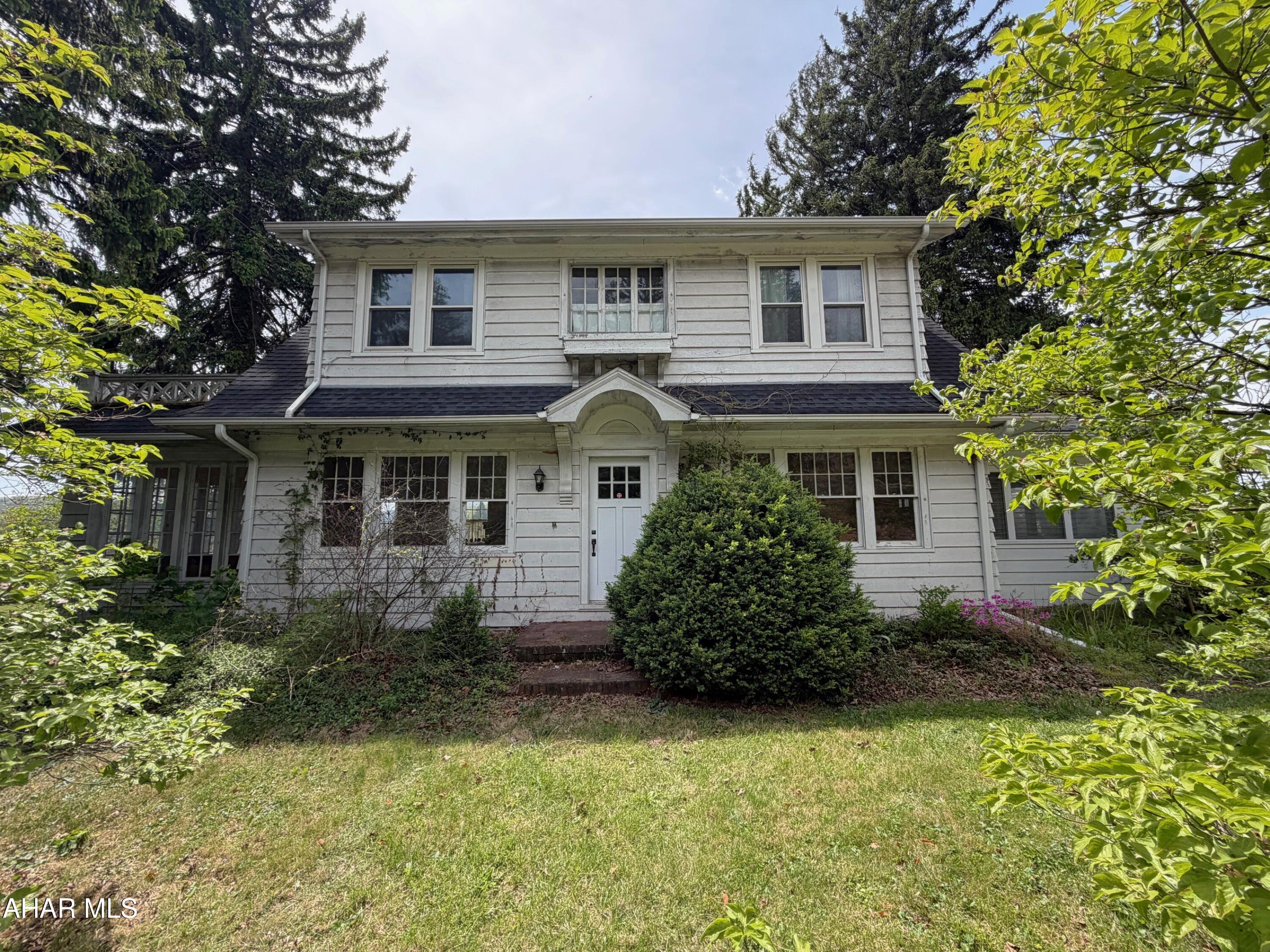 Classic 1929 Dutch Colonial brimming with character and opportunity just outside the Bedford Borough. This was a well-built home that offers timeless architectural charm and is ready for updates and remodeling to bring it back to its full potential. Featuring 4 bedrooms and 1.5 baths, the home includes a welcoming entry foyer with an open staircase, living room with wood burning fireplace, formal dining room, kitchen with eat in area, and a beautiful second-story balcony with scenic views. Relax and enjoy the double sun porches, adding extra living and entertaining space filled with natural light. Hardwoods floors and crown moldings throughout. Additional features include a full basement offering a wood burning stove, three quarter bathroom (needs all updated), oil hot water heat, and electric BB heat. Circular paved driveway and a two-story detached garage with basement storage. Large .82-acre lot with room to enjoy outdoor living, outdoor entertaining, or that big garden. Just a minute from downtown Bedford and easy access to I-99 and Lincoln Highway.