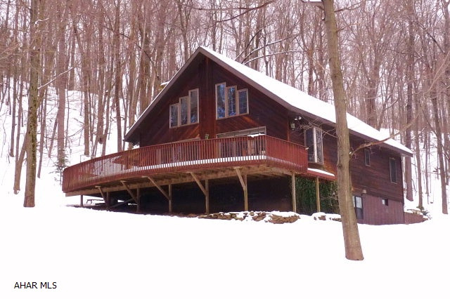A cozy 1 1/2-story 3BR/2 full a half bath rustic cedar-sided chalet style home in a picturesque 4.9 woodland country setting with stream and small pond. The main level offers an open floor plan with cathedral ceiling, exposed wood beams, kitchen, dining room and living room with a natural stone fireplace. Loft MBR suite overlooks the great room. The walkout basement is finished with laundry room, small office and family room. The over-sized detached 3-car garage features a second level shop/storage area with an attached office/studio.