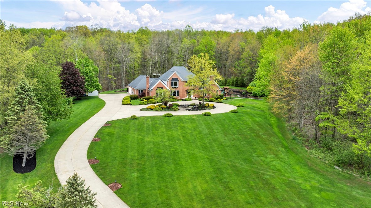 Set on 4.5 wooded acres in Timber Ridge Estates, this brick Colonial in Hinckley Township pairs refined interiors with a resort-style outdoor setting. 885 McKee Trl offers 6,152 finished sq ft (including finished basement) with a 1st-floor primary bedroom with en-suite bath, 4 bedrooms, 3.5 baths, & 3-car attached garage. The main level opens with a grand foyer, curved staircase, chandelier, high ceilings, crown molding, natural woodwork, built-ins, and newer (wood) luxury vinyl plank flooring. The eat-in kitchen features granite counters, a breakfast bar, pantry, double oven with microwave/convection upper, smooth electric cooktop, newer appliances, and views to the manicured back yard with private wooded 1/2 mile walking trail. The finished walk-up lower level adds a completely separate additional in-law/teen living suite, not included in the bedroom count, with a kitchen, full bath, living area, recreation space, newer stainless appliances, newer carpet, and fireplace. Many ADA features including an elevator that goes from the all 3 levels, extra wide door, ramp in the garage. 5 fireplaces, central vacuum, smart home features, custom blinds, newer light fixtures, updated baths, main PLUS lower laundry. Outdoors, enjoy a heated in-ground pool with waterfall & motorized hidden retractable cover, outdoor kitchen, screened/enclosed porch, black metal fence, outdoor playset, tree house, shed, fruit trees (peach, cherry, apple), vegetable garden, clover and wildflower areas that attract butterflies & pollinators, terraced landscaping with perennials, and a bridge over the creek. Other features: circular drive, additional parking pad (great for RV, boat, etc), 2x6 construction, roof/gutters 2012, tankless hot water 2023, A/C 2019, and no pesky HOA. Just minutes to Hinckley Reservation, Highland Schools, shopping, restaurants, enjoy serene rural living with nearby city amenities.