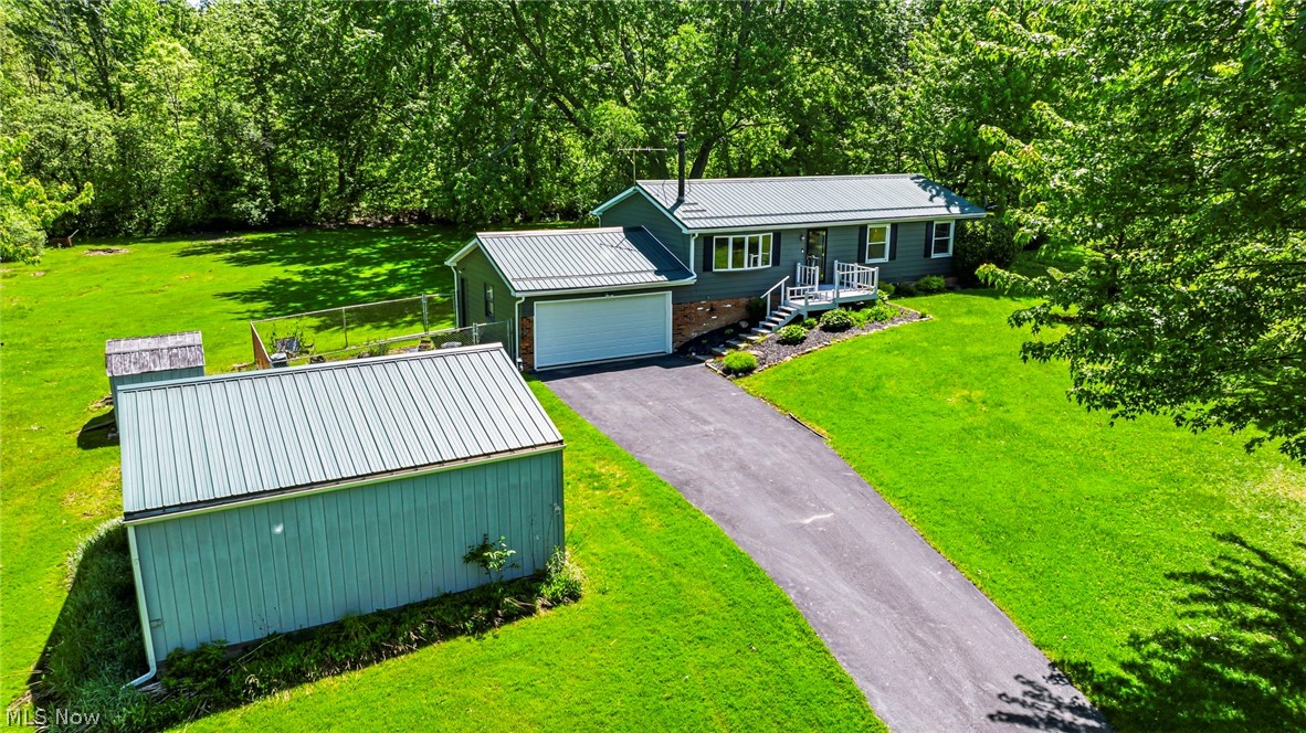 Welcome home to this charming three-bedroom ranch nestled on a sprawling, beautifully wooded five-acre parcel in peaceful Montville Township. Built in 1976, this single-family residence perfectly balances classic country living with an abundance of indoor and outdoor space. The main floor boasts hardwood flooring throughout the bedrooms and bright living area with a classic wood/coal burning stove for chilly evenings. Durable ceramic tile in the entry and dining area lead to the rear deck, perfect for relaxing or entertaining. The kitchen has ample counter and cabinet space and newer appliances. The updated main-floor bathroom with walk-in tiled shower completes the main level. 
Downstairs you will find a partially finished basement that can significantly expand your usable living space. Currently set up as a woodshop and can easily be changed for your personal needs. A laundry area, wet bar, second full bath, and additional storage with steps up to the garage complete the lower level.  Step outside onto the back deck to enjoy peaceful, private views of your expansive treed yard and garden area.
Car enthusiasts, hobbyists, or anyone needing extra storage space will fall in love with the exceptional parking configuration, which includes a two-car attached garage and an additional two-car detached garage/outbuilding. All with Metal Roofs and 50 year warranty. Located within the Berkshire Local School District, this move-in-ready property offers immediate possession at the time of transfer. A one year Home Warranty is offered for buyer's peace of mind. Showing availability is handled via the showing service link, allowing you to easily schedule a tour to experience this wonderful Geauga County gem.