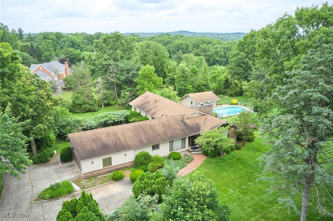 Situated on a gorgeous and private 2.1-acre lot in Bath, 2265 Anthony Drive offers 4 BRs, 4.5 baths, private wooded views, a pool & more!  Large and open foyer leads to a dramatic living room with floor-to-ceiling brick look-thru fireplace, pitched ceiling, and windows that overlook a private backyard.  The family room is on the other side of the gorgeous look-through fireplace with wood-paneled walls and great views.  The dining room features lots of windows and leads easily to the eat-in kitchen with updated granite counters, suite of stainless steel appliances, recessed lighting, and lots of cabinets.  A large slider leads to a private patio and lets in tons of natural light.  New stationary window next to slider and new screens.  The back hall also features tons of storage and a large pantry cabinet.  The 1st floor also features a convenient half bath.  Upstairs you'll find 4 large bedrooms including a primary suite overlooking the pool with en suite primary bath and three large additional bedrooms, 2 with a Jack and Jill bath between them and the third bedroom with a nicely updated hallway full bath.  A large rec room with sliders out to the backyard and pool, a built-in bar, a full bath and laundry make up the great walkout lower level.  There is also unfinished storage a few steps down.  So much fun to be had in the in-ground pool!  Shed/outbuilding with lots of storage, pull-through doors and roof updated approx. 20 years ago.  The 2.1-acre lot gently rolls and provides plenty of space for recreation, gardening, whatever you want.  Don't miss this great home on a private beautiful street minutes from Sand Run Metro Park, Hale Farm, the Cuyahoga National Park & more.  Award-winning Revere schools!