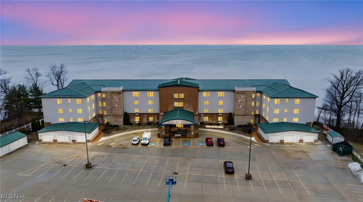 Enjoy breathtaking Lake Erie views from this stunning 3-bedroom, 2-bath condo located on the 4th floor of a sought-after lakefront community in Geneva-on-the-Lake. This spacious and inviting unit features an open-concept layout with a large eat-in kitchen showcasing stone countertops, stainless steel appliances, white cabinetry, and a breakfast bar that opens to the bright living area. The living room offers high ceilings, an electric fireplace, and direct access to a private balcony with beautiful views of Lake Erie—perfect for morning coffee or evening sunsets. The primary suite includes a walk-in closet and a private bath with a double vanity and walk-in shower. Two additional bedrooms, a full guest bath, and convenient in-suite laundry provide space and comfort for all. This condo also includes a detached Garage #7 plus parking for two vehicles. Community amenities feature a heated indoor pool, fitness room, community room, private beach, and pier for enjoying everything lake life offers. Ideally located just minutes from award-winning wineries, scenic parks, dining, and entertainment options, this condo is perfect as a year-round residence, weekend getaway, or investment opportunity. Experience the best of lakeside living in one charming and move-in-ready package!