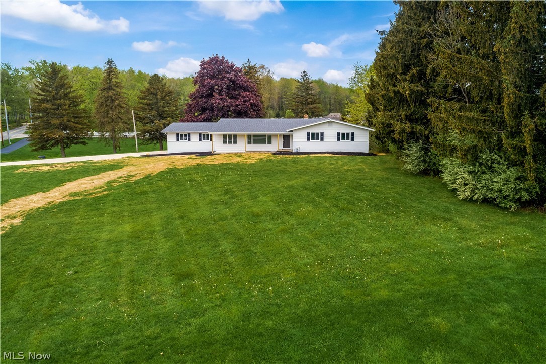 It doesn't get much better than this stunning ranch perched on over an acre lot in Brimfield Twp with newly installed access to public water and sewer! Completely renovated inside and out with high-end, quality finishes! The covered front porch leads into the living room with large windows that flood the space with natural light. Newly refinished hardwood floors throughout the entire first floor are a warm contrast to crisp white trim and molding. This kitchen is a total knockout...featuring two toned, soft-close cabinetry, stainless appliances, tiled backsplash, quartz counters and a massive center island! The adjacent great room has a cozy fireplace and access to the new deck overlooking the backyard. The guest bathroom is remodeled with modern finishes, tile flooring and a tiled tub surround! Three generously sized bedrooms include a spacious owner's suite with a remodeled en suite bath featuring a custom tiled shower and a white vanity topped with a quartz countertop. The finished,