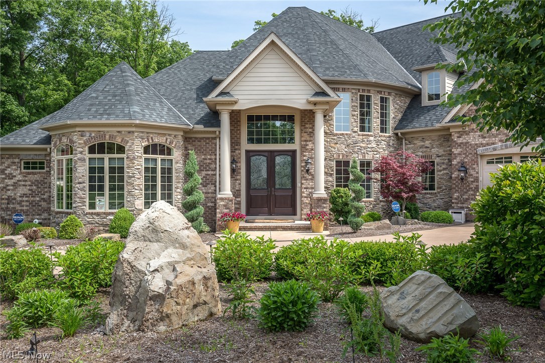 Absolutely gorgeous & remarkably appointed custom ALL brick & stone home in impeccable condition, on 2.0 stunning & private park-like acres, offers spectacular views of the pristine landscaping, waterfall feature, low lying stream, woods, stamped concrete patio & walkways, firepit, foot bridge, Trexx Deck, & heated outdoor kitchen with new gas grill, bench seat, fireplace, vaulted wood ceiling, pizza oven, sink, removable windows & more! This home is best suited for those who love to entertain inside and out. The home has high ceilings, very open floor plan, exquisite luxury finishes & architectural details, tons of closet & storage space, an elevator that services ALL 3 levels, & upper & lower heated garages that can house up to 10 cars plus a car lift & workshop. There is a large 2 story foyer with coffered ceiling, a library with built-ins, great room with a stunning coffered ceiling, an open concept gourmet eat-in kitchen with adjoining dining room & a hearth room with fireplace &