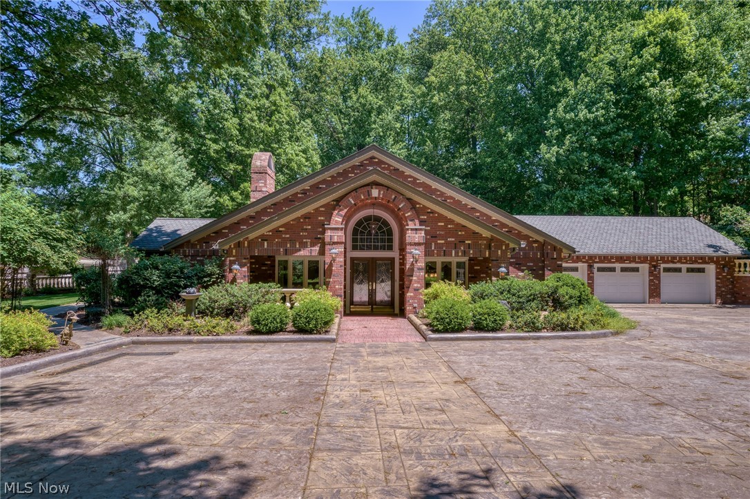 Welcome to the ultimate entertainer’s haven! Nestled on 2.48 acres of forested privacy, this one-of-a-kind 3,944 sqft brick estate-caliber ranch is the ultimate canvas for those who love to host. Massive multi-purpose rooms built for large-scale entertaining, equally suited to formal soirées and lively game nights, seamlessly transition to extraordinary outdoor spaces. Set behind a gated entrance, this property immediately conveys the epitome of privacy, craftsmanship and grandeur. The wooded approach unfolds along a stamped driveway with inlaid lights, arriving at exquisite grounds defined by magnificent hardscaping. The home opens to a 654 sqft multi-functional space that integrates a fireplaced family room, game and lounge area, and full-service wet bar into a welcoming and dynamic destination, which can be closed off to contain noise during gatherings. A sliding door connects to a sunroom with outdoor access; this versatile room also functions as a gym or office. The 754 sqft formal dining/living area bestows refined entertaining and leisure, finished with a rich wood-clad ceiling and a dual-sided fireplace that frames an intimate sitting area. Both spaces access your outdoor oasis boasting 717 sqft of covered porches elegantly detailed with wood-clad ceilings and Nature Stone flooring, a ~263 sqft paver patio, stamped walkways, a tranquil water feature, and pickleball/basketball half-court (overflow parking). The 289 sqft kitchen boasts a skylit cathedral ceiling, extensive storage, and sprawling countertops + massive island. Cabinetry continues into the dinette, offering exceptional storage/serving space. Dual offices with built-ins are ideal for a home business or creative pursuits. 2.5-car heated garage is meticulously finished with Nature Stone, storage closets, worktops. Half bay accommodates ATVs, lawn equipment. 384 sqft masonry shed + attic. Whole house generator! A versatile entertainment-ready design promising a lifetime of unforgettable gatherings!