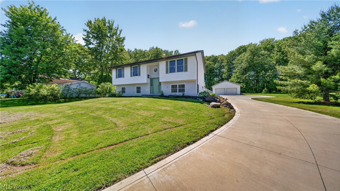 Welcome to this beautifully updated split-level home in Kirtland, offering a premium amount of space and endless flexibility! With 5 spacious bedrooms, this layout provides incredible opportunity for a dedicated home office, playrooms, or guest suites. The main level boasts a bright, open-concept kitchen, dining, and living area that is perfect for entertaining, complete with a large island and seamless access to a massive, two-level partially covered back deck. Down the hall, three convenient bedrooms include a primary bedroom with a pocket door for direct access to the main bath, which features classic white subway tile and a freestanding soaking tub. Downstairs, the finished lower level expands your living space with a large recreation room, a second updated full bath, an additional sunlit bedroom, flex room, and a practical mudroom/utility room. Outside, enjoy a large, naturally shaded yard and a detached 2-car garage with an expansive concrete pad. Move-in ready and loaded with updates—schedule your tour today!