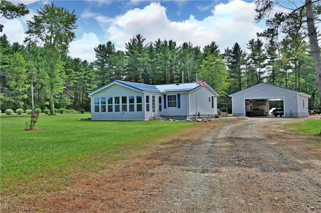 This large rural complex sits on over three acres of beautiful, tree lined land. Entrances from both cross streets allow easy access to the home and outbuildings. A modular ranch home sits in the middle of the property, showcasing a handsome blue steel roof and gray siding. A matching oversized detached garage offers huge workspace or parking with a concrete pad beneath. Inside the home, an open floor plan offers bright and comfortable living space.  Arched ceilings provide unique styling with natural colored carpets. A newly updated kitchen and dining area with a lengthy countertop divides the space while providing tons of meal prep and serving surfaces. White cabinets wrap  around and down a sort hallway were a galley style layout becomes dominant. Laundry service is located at the end of the hall.  The brightly colored adjacent family room is complimented by hardwood style flooring which continues into the eat in dining area. A relaxing sunroom is visible through a trio of windows.