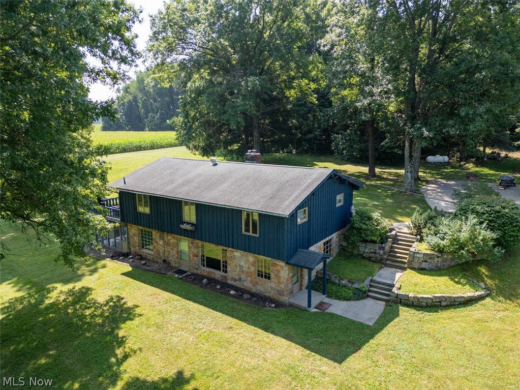 A rare opportunity to own a remarkable piece of Ohio history! Nestled on over 5 picturesque acres, this completely renovated 4- bedroom, 2-bath home seamlessly blends historic craftsmanship with modern luxury. Built on the footprint of the original Simon Perkins Jr. barn, the home incorporates reclaimed materials from the historic 1866 structure, including hand-hewn beams, reclaimed wood, stonework, and extraordinary architectural details that simply can’t be recreated.
The stunning chef’s kitchen features leathered granite countertops, a 36” Italian Hallman dual-fuel range, custom cabinetry, and beautiful finishes. The custom hand-painted copper stair risers, inspired by the home’s original copper gutters and spouting, create a one-of-a-kind focal point.
Designed for comfortable living and entertaining, the home offers two spacious living areas, including a dramatic great room with vaulted ceilings, exposed wood beams, a striking stone fireplace, and walls of windows that fill the space with natural light.  All bedrooms are generously sized and showcase quality craftsmanship throughout.
Enjoy two incredible outdoor living spaces, including a screened-in porch and an expansive second-story deck overlooking the peaceful 5-acre setting. A large outbuilding with two oversized garage bays provides endless storage, workshop space, or hobby opportunities.
Recent improvements include a new propane boiler, well pump, central air and heat pump, professionally stained exterior, updated electrical service, and extensive renovations throughout the home.
This is more than a home—it’s a rare opportunity to own a beautifully restored piece of Northeast Ohio history.
