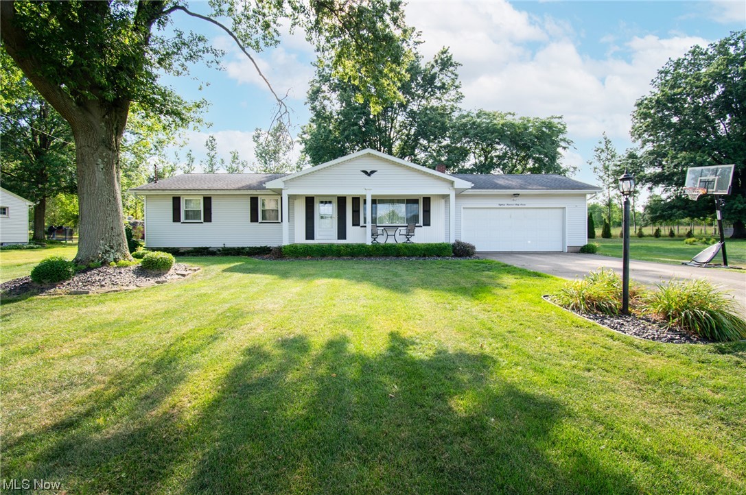 Quiet 3 bedroom, 1.5bath ranch in Columbiana nestled on a half acre. Entering the property on the covered front porch, you are greeted by a nicely sized living room with natural hardwood floors that carry through the eat-in kitchen and into all of the bedrooms. Ample cupboard and counter top space in the kitchen; cooktop, built in microwave, wall mounted stove, dishwasher, and refrigerator are included in the sale. Enjoy additional finished square footage with a functioning wood burning stove in the basement. Excellent view of the wooded back yard from the enclosed sun porch off the back of the home. Low maintenance landscaping with modern black stone, nicely pruned shrubs, and matured trees for a nice shady retreat. Plenty of storage in the attached 2 car garage as well as an attached storage shed.  Energy efficient double hung vinyl windows for easy cleaning. Washer and dryer also included. A One Year Home Warranty is being provided for additional coverage.