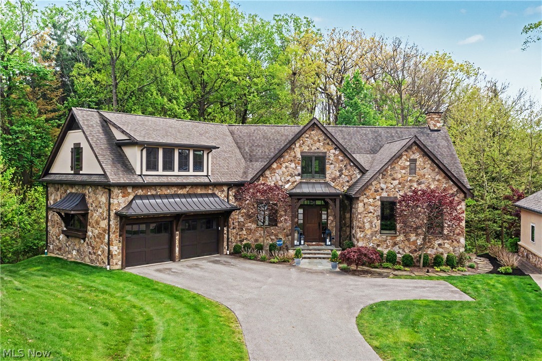 Set on a beautifully wooded lot in Moreland Hills, this exceptional newer-construction residence blends refined contemporary design with the comfort and functionality of everyday life. A dramatic great room serves as the heart of the home, featuring soaring cathedral ceilings, hand-hewn wood details, a striking modern fireplace, and walls of windows that frame serene wooded views. The space flows seamlessly into the chef’s kitchen, appointed with premium stainless steel appliances, quartz countertops, a brick backsplash, and generous prep and gathering space. A screened porch and deck extend the living areas outdoors, creating effortless indoor-outdoor flow. The first-floor primary suite offers a luxurious retreat with a vaulted ceiling, private fireplace, direct access to a secluded porch, a spacious walk-in closet, and a spa-inspired bath with custom tilework and a five-fixture design. An office with a full wall of built-ins, along with a laundry room, mudroom, and powder room, complete the main level. Upstairs, a central loft flows into two spacious bedroom suites, each featuring a walk-in closet and private ensuite bath. The walk-out lower level is designed for both entertaining and relaxation, offering a private guest suite, patio access, a game room, home theater, and fitness area with direct access to the outdoors. Outside, a private patio overlooks the peaceful, tree-lined backyard. Additional highlights include radiant heated flooring throughout the main level and an ensuite bath for every bedroom. Combining sophisticated style, thoughtful design, and exceptional amenities, this remarkable Moreland Hills home offers a truly elevated lifestyle in a private natural setting.
