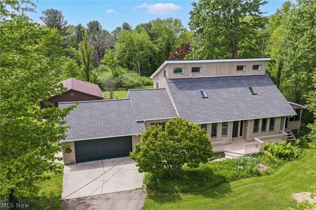 One-of-a-kind contemporary home nestled on 1.66 wooded acres on a quiet cul-de-sac in Munson Twp, located in the Chardon School District. Offering 3 bedrooms, including a 1st-floor primary, 2.5 baths & over 2,602 living sq ft w/ a finished walkout lower level, this unique property combines architectural character, flexible living areas & exceptional outdoor amenities, including a front deck, 2 rear decks, 2 balconies, screened porch, firepit, large garden space, shed, attached 2-car garage & a 32' x 40' outbuilding that can house up to 6 vehicles. The open-concept interior is filled w/ natural light from numerous skylights & features soaring vaulted ceilings throughout. An eat-in kitchen is highlighted by butcher block countertops, stainless steel appliances, center island w/ breakfast bar & a stunning wood-planked beamed ceiling. The vaulted 2-story family room creates an impressive gathering space, while the vaulted dining room provides deck access for seamless indoor-outdoor living. The 1st-floor primary suite offers private deck access & en-suite bath w/ double vanity & tiled Roman shower. A 1st-floor office w/ access to the screened porch provides an ideal work-from-home setup. Other bedrooms feature balcony access, 1 w/ a loft space & 1 w/ sitting area, creating unique & versatile retreats. The lower level expands the living space w/ a rec room & built-in wet bar, while the unfinished area includes built-in workshop shelving for hobbies, projects, and storage. RECENT UPDATES include: Replaced roof (2025), septic system (2024), HVAC (2021), water softener, fridge & dishwasher (2024), remodeled upstairs bath & 1/2 bath (2025) & more! INCLUDED are ALL kitchen appliances, washer/dryer, TV mount, office desk, skylight smart control system. Conveniently located near OH-44, US-322, UH Geauga Med Center, schools, parks, restaurants & other local attractions.  A rare opportunity to enjoy privacy, character, and exceptional functionality in a truly distinctive home.
