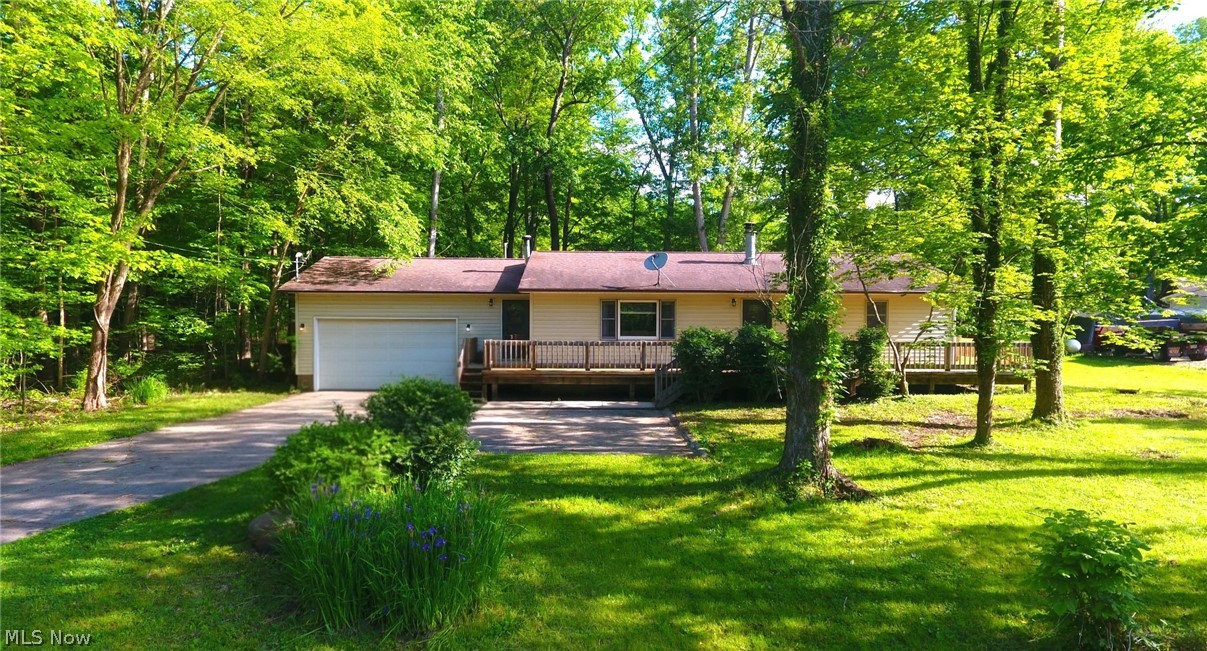 Fantastic opportunity to own this spacious ranch tucked away on a private, rural wooded lot. Very nice curb appeal as you pull into an oversized concrete driveway and a wraparound deck! New insulation throughout along with leaf guards on all of the gutters. All three bedrooms are nice sized with large closets. Eat-in kitchen with ample cabinet space, large window over the sink looking into the rear yard and all appliances will stay. You'll enjoy the rustic warmth with the woodburning fireplace in the spacious living room that also has a dining area, beamed ceilings and large picture window. Two car attached garage has lots of room for you to add workbenches or store misc. items. Located in the very desirable James A. Garfield school district! Within minutes to State Route 422, 82, 88 and downtown Garrettsville.