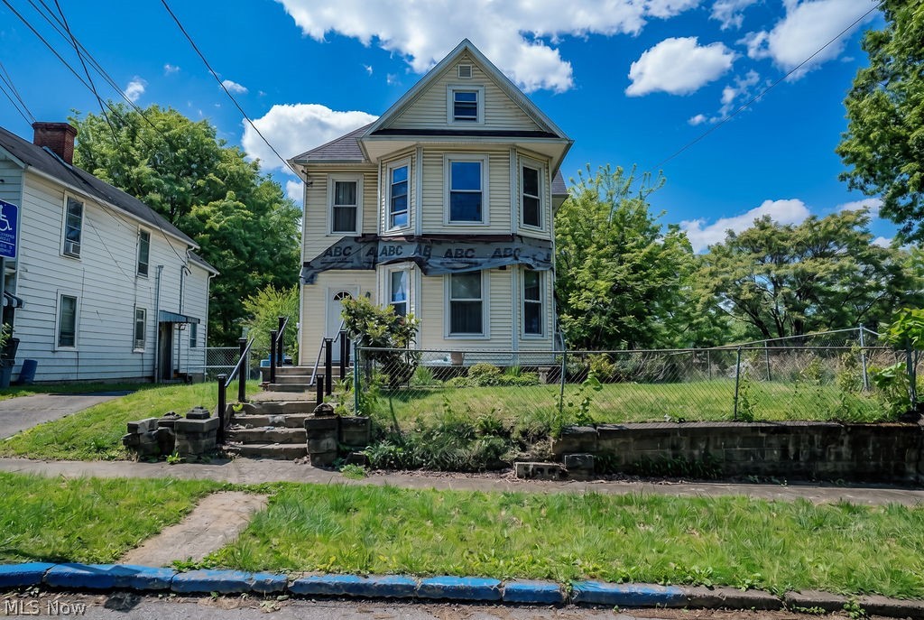 Some houses whisper. This one practically dares someone to bring it back to life. Built in the late 1800s, this oversized Victorian-inspired home still carries the kind of character you simply cannot recreate today. From the moment you step through the front entry, the staircase becomes the centerpiece, framed by original-style details, decorative trim, crown molding, and tucked-away storage beneath the stairs that feels straight out of another era.
Pocket doors open into a striking living room where oversized windows wrap the space in natural light and a decorative fireplace anchors the room with vintage charm. The dining room continues the story with exposed brick, recessed lighting, and another dramatic window arrangement that gives the home its unmistakable architectural personality.

The kitchen blends updates with opportunity, offering wood cabinetry, stainless appliances, gas range, glass tile backsplash, oversized sink, breakfast area potential, laundry hookup, and space ready for a future island centerpiece. Two renovated full baths feature tile surrounds, glass tile accents, and upscale finishes including one with a dual-head walk-in shower and the other with a deep soaking tub.

Upstairs, the massive hallway creates additional flex space while the bedrooms continue the home's distinctive design with angled window alcoves, exposed brick details, and generous closet areas including a large walk-in setup in the front bedroom.

Outside, the mostly fenced yard, concrete front porch, remaining architectural posts to erect, and rear deck all hint at what this property could become with vision and restoration. The home does need repairs and finishing work, but the hard-to-find details, scale, and craftsmanship already here make the potential impossible to ignore.

This is the kind of project people wait years to find.