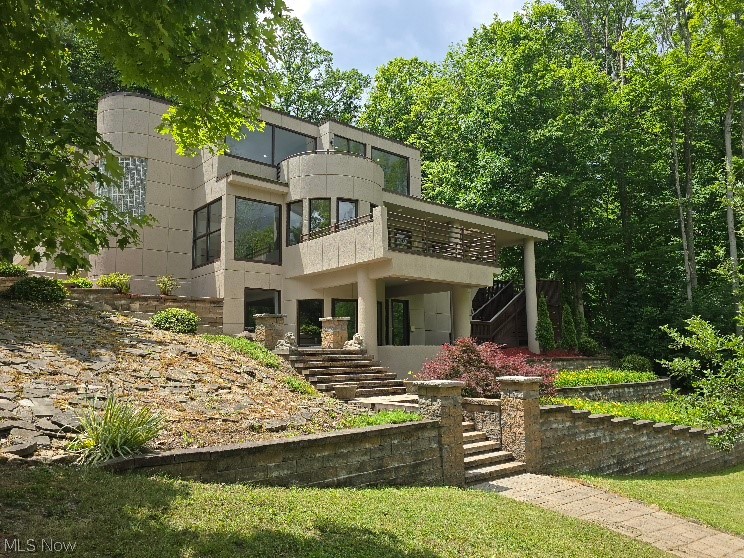 A one-of-a-kind contemporary stucco masterpiece has arrived on the market! From the moment you enter the property, you'll be captivated by the long private winding driveway leading to this spectacular estate. Shoot hoops on the basketball area before crossing the charming bridge, and take in the breathtaking, wooded 150' x 430' lot backing directly to the Metroparks on 2 sides. With parking for more than 10 vehicles and a spacious 2.5-car garage, there's plenty of room for family and guests.The outdoor setting is truly exceptional, featuring a peaceful water lily pond, stunning landscaping, asian pears and apples impressive retaining walls accented with LED lighting, and a stamped concrete patio perfect for entertaining. Multiple decks provide outdoor access and scenic views at every turn, creating a seamless connection between indoor and outdoor living. Inside, the kitchen showcases beautiful cherry cabinetry, granite countertops, stainless steel new electric stove. Expansive windows throughout the home flood the space with natural light and offer picturesque views of the surrounding landscape.The spacious living room features a cozy gas fireplace, while the first floor offers the convenience of a bedroom or den and full bath. Upstairs, you'll find three additional bedrooms, including a generous primary suite complete with double-door entry, ample closet space, and a private full bath. Newer 2nd floor bath.The walkout lower level offers exceptional additional living space at ground level, filled with natural light and easy access to the home's multiple decks. Whether you're entertaining, working from home, or simply relaxing, you'll appreciate the spacious family room, beautiful desk area, and generous crawl space for all your storage needs. For added peace of mind, the roof, furnace, and air conditioner were all replaced in 2020. This extraordinary property combines privacy, nature, and contemporary style in a setting that is truly unmatched.