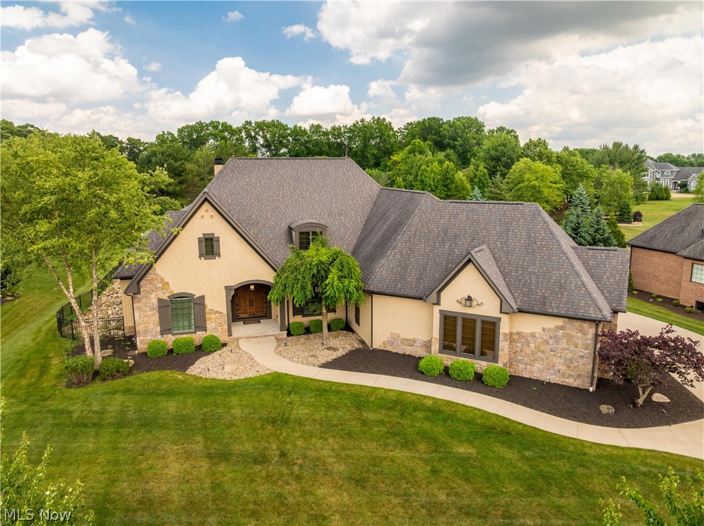Experience the ultimate in luxury living and entertaining in this exceptional custom ranch nestled within the desirable Greenwich Place community of Jackson Township. Situated on a picturesque 0.82-acre lot, this stunning brick and stucco residence offers an impressive combination of elegance, comfort, and one-of-a-kind amenities. A grand foyer welcomes you into a thoughtfully designed split-bedroom floor plan highlighted by soaring beamed cathedral ceilings, rich architectural details, and expansive living spaces. The inviting great room centers around a beautiful fireplace and flows effortlessly into the spacious eat-in kitchen and sunroom, creating the perfect setting for everyday living and memorable gatherings. The luxurious owner's suite is a peaceful retreat complete with an ensuite bath and private sliding doors leading directly to the backyard oasis. Two additional bedrooms are connected by a Jack-and-Jill bathroom, offering privacy and convenience for family and guests alike. A dedicated front office and first-floor laundry add both functionality and flexibility. Designed for entertaining on every level, the finished lower level is truly extraordinary. Host family and friends in the expansive recreation room featuring a kitchenette, bonus room, and dedicated exercise space. The show-stopping indoor basketball court sets this home apart from the rest, offering a rare opportunity to enjoy year-round recreation without leaving home. Step outside to your own private retreat. The expansive patio overlooks a sparkling in-ground pool and beautifully maintained grounds, creating the perfect backdrop for summer gatherings, outdoor entertaining, and quiet evenings under the stars. Built in 2012 and offering 3 bedrooms, 2 full baths, 2 half baths, and a 4-car garage, this remarkable residence delivers an unmatched lifestyle where luxury, recreation, and comfort come together seamlessly. A truly exceptional property that must be experienced to be appreciated.