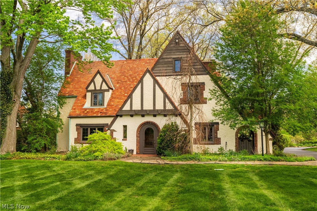 Nestled on a rare nearly one-acre double lot in the highly desirable Avondale neighborhood, this timeless Tudor-style residence offers an exceptional blend of elegance, architectural character, and private estate-like living. Surrounded by mature trees and lush landscaping, the striking stucco exterior sets the stage for this one-of-a-kind property. Step inside the impressive foyer with a walk-in coat closet and experience the warmth and craftsmanship throughout the home. The spacious living room is filled with natural light and anchored by a stunning fireplace. Rich hardwood flooring enhances the formal dining room, while the kitchen flows into a charming breakfast nook. A private first-floor office or den offers flexible living space, and the sunroom with slate flooring overlooks the backyard sanctuary. Upstairs, a cozy study area adds character and functionality. The spacious owner’s suite provides a peaceful retreat designed for comfort and relaxation. A private guest suite with its own full bath and separate staircase offers ideal accommodations for visitors or multi-generational living. Two additional generously sized bedrooms and another full bath complete the second level. The lower level expands the living space with a large recreation room featuring a striking stone fireplace, laundry area, and workshop space. Built-ins throughout the home add timeless charm and functionality. Outside, enjoy your own private outdoor oasis featuring gardens, mature landscaping, an underground sprinkler system, and direct water access to the vegetable garden. The heated three-car garage showcases brand-new garage doors and durable epoxy flooring. Rich in architectural detail and timeless craftsmanship, this remarkable Avondale property offers a rare opportunity to own a home that perfectly blends elegance, comfort, and privacy. Ideally situated near shopping, dining, parks, and schools, this distinctive residence delivers exceptional space and unmatched appeal throughout.