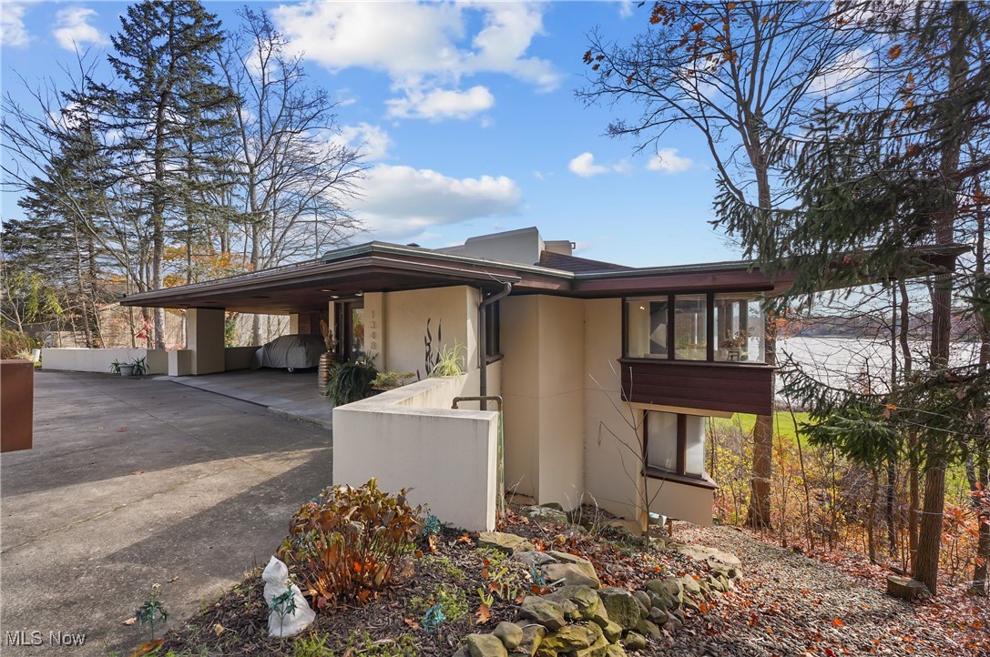 Inspired by Frank Lloyd Wright, this stunning lakefront home is a Mid-Century Modern masterpiece in desirable Twin Lakes. Perched on a hillside overlooking West Twin Lake, it offers dramatic rooflines, wrap-around balconies, and floor-to-ceiling windows that bring the outdoors in. The redesigned chef’s kitchen features rich redwood cabinetry, updated backsplash, Thermador top-of-the line appliances, custom floating shelves, and custom built island with pop-out cabinets and bar seating. The open layout flows into the dining and living areas, where walls of windows capture breathtaking sunrises. Cozy, newly upholstered built-in seating and a gas fireplace create the perfect setting for winter evenings.  Thoughtfully curated details include warm redwood accents, built-in cabinetry, integrated lighting, refinished concrete and luxury vinyl tile flooring. This 4–5 bedroom, 2.5-bath home provides flexible spaces for modern living and work. The primary suite wing offers that magnificent view, deck access, walk-in closet and updated bath with walk-in shower & there's a sitting/office area. A lower-level family room adds another comfortable gathering space.  The walkout lower level leads to a spectacular three-tier Unilock patio system that cascades down the hillside, offering multiple areas for dining, entertaining, and enjoying panoramic lake views. Launch your kayak from your backyard and enjoy the seamless indoor-outdoor lifestyle this home was designed to deliver.  With its overhanging eaves, horizontal lines, and strong connection to nature, this home is a true work of art. Updates include: built-in sofa cushions (2024); updated bathrooms (2023); redesigned kitchen, gas fireplace conversion, refinished concrete floors (2022); custom trim (2021); LVT flooring and hot water tank (2020); new furnace, AC, and front stucco (2018); three-tier Unilock patio and replaced skylights (2016).  This property is a rare, one of a kind, iconic property—and not to be missed.