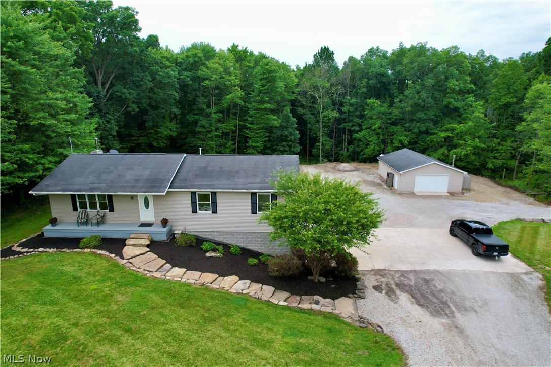 Welcome to this quality-built ranch home nestled on over 6 picturesque acres in a prime Carroll County location! This beautifully maintained 3-bedroom, 2.5-bath home offers exceptional craftsmanship throughout, featuring gorgeous hardwood cabinetry, custom woodwork, hardwood railings, high-end lighting, and numerous quality finishes. Enjoy the peaceful country setting while remaining just minutes from Carrollton, Waynesburg, Malvern and surrounding communities. Atwood lake is 10 minutes away! The main level features a spacious kitchen with abundant cabinet space, a formal dining area with sliding doors leading to a deck overlooking the private backyard, and three generously sized bedrooms. The owner’s suite includes a large walk-in closet, jetted soaking tub, and walk-in shower, while the additional bedrooms also offer oversized walk-in closets. The finished walkout lower level is perfect for entertaining, offering a large family room, half bath, laundry room, utility room, and access to a covered patio beneath the deck with a beautiful paver sitting area. The home is also equipped with a wired smoke/fire alarm system and security system for added peace of mind. Outside, you’ll appreciate the outstanding curb appeal, including custom stone steps and walkways crafted from rocks found right on the property. Wildlife is abundant, with deer and turkeys frequently seen throughout the wooded acreage. 2 car attached garage is finished and clean. The expanded driveway features a full turnaround with plenty of room for large trucks, trailers, or even semi-truck access. Completing the property is a 30x40 insulated outbuilding with a woodturner and space for up to four vehicles, equipment, or hobbies. If you’re looking for a quality-built home with privacy, acreage, abundant wildlife, and convenience, this one is a must-see! Schedule your private showing today.