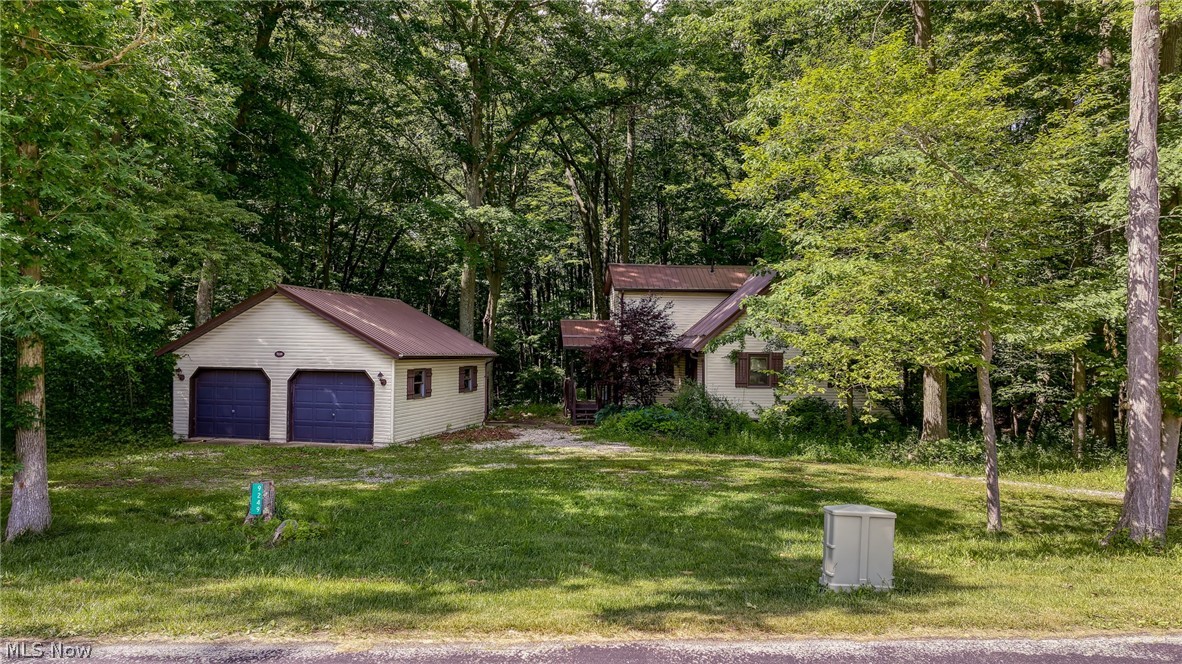 Tucked away on 3 secluded wooded acres, this charming Cape Cod offers the kind of privacy and peaceful setting that's becoming harder to find. Surrounded by mature trees, scenic hillside views, and winding hiking trails throughout the property, every day feels like a retreat. Spend evenings around the fire pit, relax on the screened porch, or unwind on the back deck overlooking your own private forest. And when you're ready for the water, West Branch State Park Marina and Beach are just 7 minutes away. Inside, the home is full of warmth and character with a spacious great room featuring soaring wood plank cathedral ceilings, built-in accents, and expansive windows that bring the outdoors in. The open-concept kitchen, dining area, and living room create the perfect gathering space while showcasing beautiful backyard views. The main level also offers three bedrooms and an updated full bath. Upstairs, you'll find a private primary suite complete with its own full bathroom and an open loft-style overlook of the great room below, adding to the home's cozy cottage feel. The walkout lower level is where your vision can truly shine. Already framed with drywall in place and plumbing for a half bathroom, the space is well on its way to becoming an incredible extension of the home. It features a large rec room, two bonus rooms, and a laundry area but will require paint, flooring, trim, and finishing touches to bring it to completion. Overall, the home could benefit from TLC, making it an outstanding opportunity for someone looking to build equity while creating their dream retreat. Additional highlights include a new metal roof (2019), water softener (2025), detached two-car garage with overhead storage, a quiet country road, and a setting that feels worlds away while remaining conveniently close to everyday amenities. If you've been searching for privacy, character, and endless potential, this hidden gem is ready for its next chapter. Call now to schedule a private showing!
